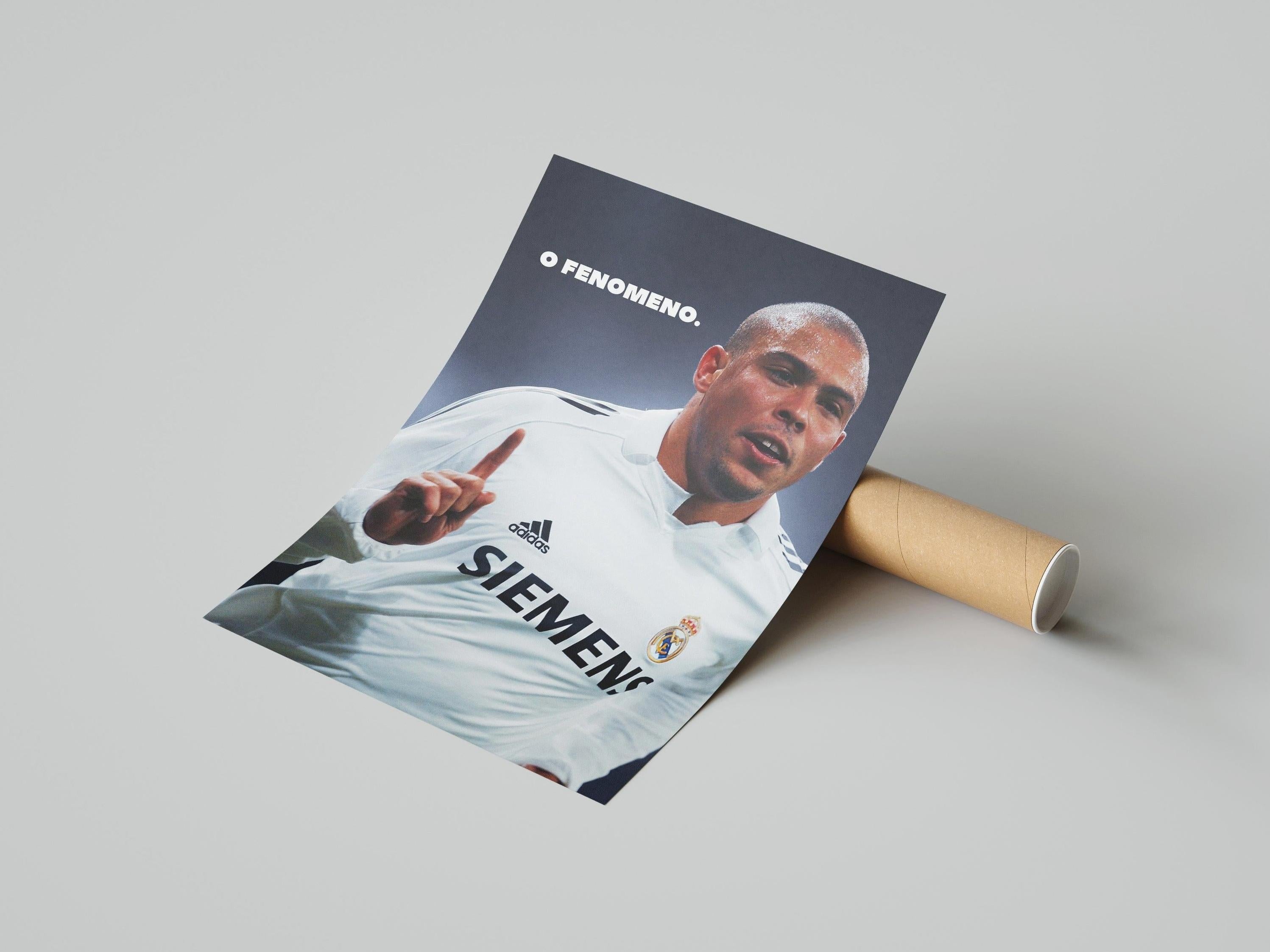 The Ronaldo O Fenômeno Poster by Retro1999 shows him in a white SIEMENS jersey, finger raised, with O FENOMENO. above. A must-have for Real Madrid and Santiago Bernabeu fans. Rolled format; classic light background.