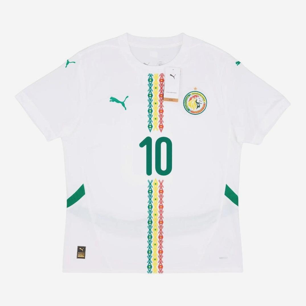 The Senegal 2024-25 Home Shirt by Retro1999 features a white base with green accents, the number 10, bold vertical patterns, Puma logos, and the national crest—blending classic Senegalese football spirit with retro design.