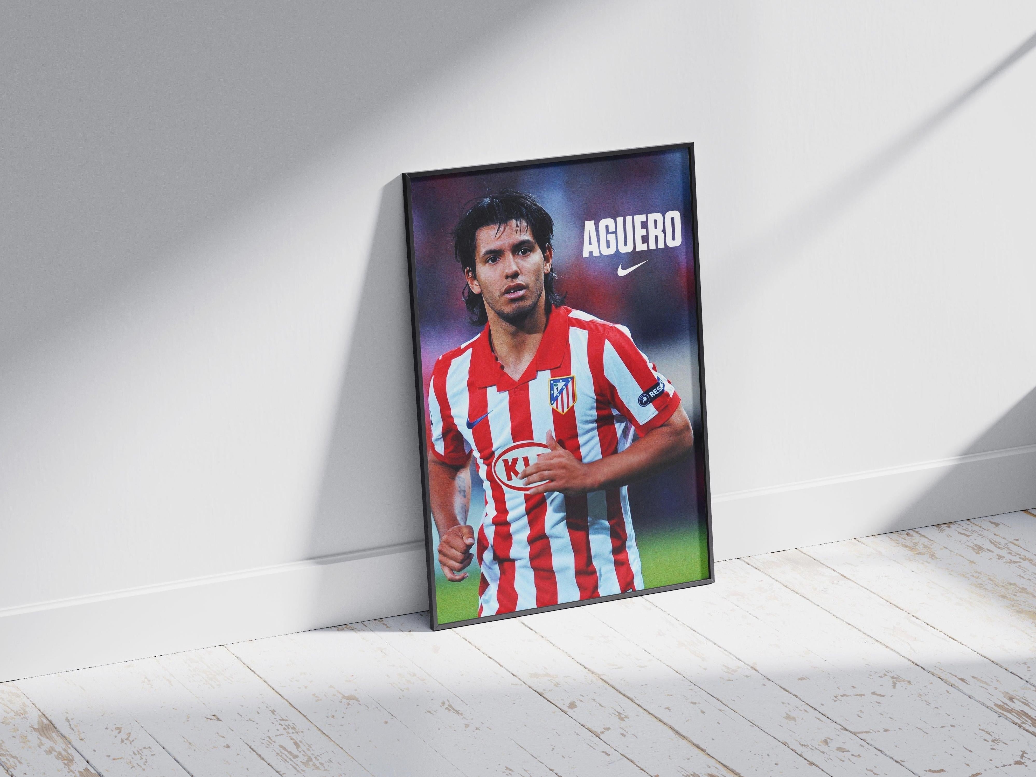 The Sergio Aguero x Atletico Madrid Poster by Retro1999 features the soccer star in a red and white striped jersey, Nike logo above, leaning against a white wall—perfect football memorabilia for any fan.