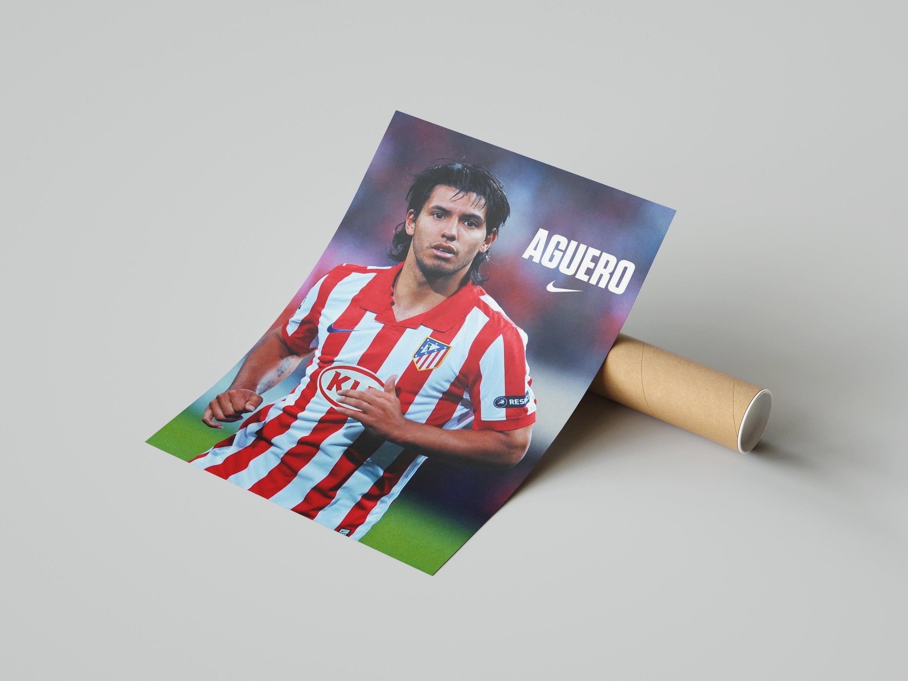 The Sergio Aguero x Atletico Madrid Poster by Retro1999 shows Aguero in a red and white striped kit with Nike logo, rolled and displayed on light gray—a must-have for football memorabilia collectors.