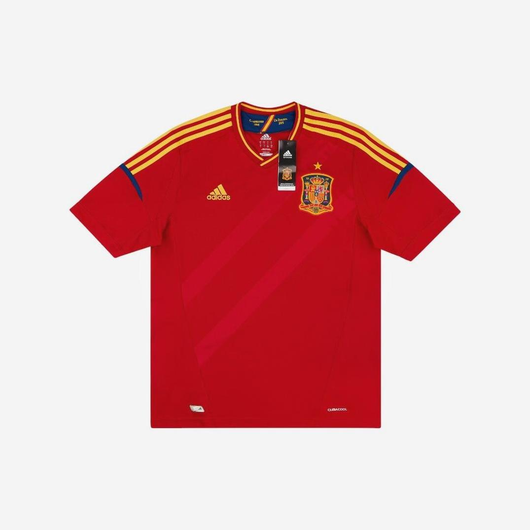 The Spain 2012 Home Shirt by Retro1999 features yellow Adidas stripes on the shoulders, team crest on the left chest, Adidas logo on the right, 2010 FIFA World Cup patch under the collar, and original tags attached—a must-have for football fans.
