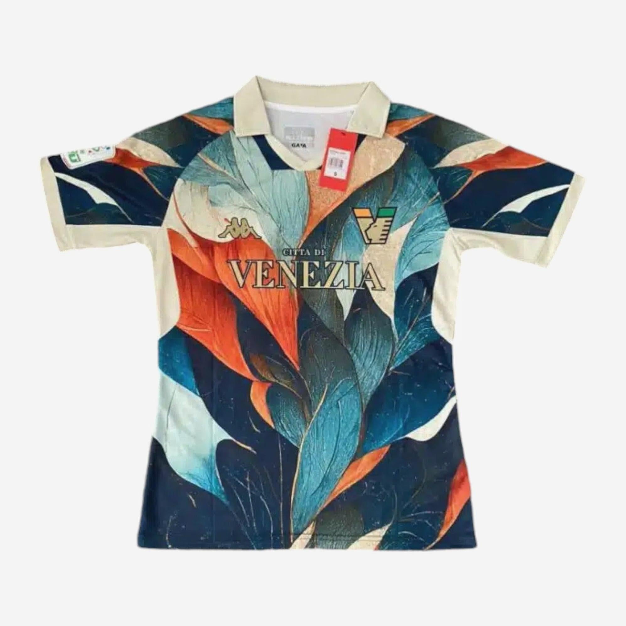 The Retro1999 Venezia 2022-23 Special Edition jersey sports a bold feather-like blue, teal, orange, and cream pattern with cream sleeves and collar, plus CITTA DI VENEZIA text and logos on the chest.