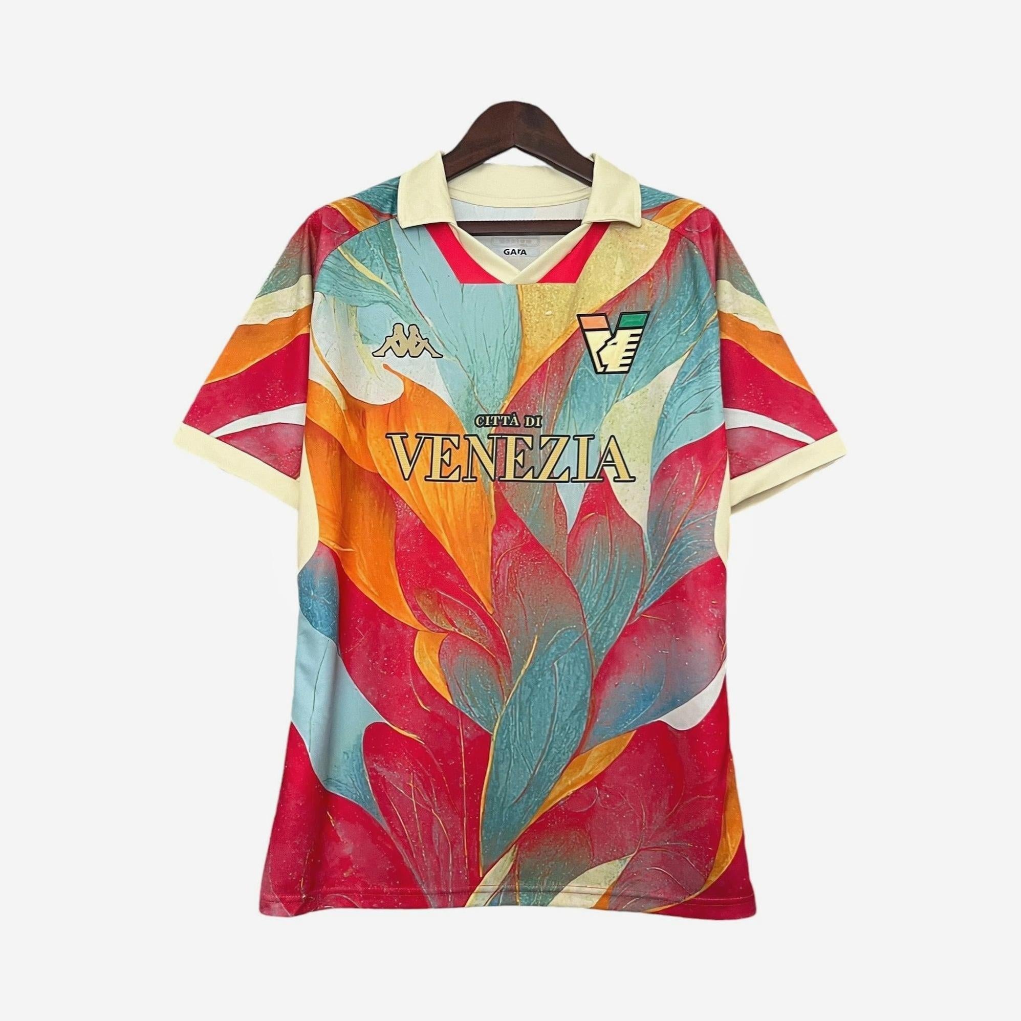 The Retro1999 Venezia 2024-25 Special Edition football shirt features bold, abstract feather patterns in red, teal, orange, and yellow with cream collar and cuffs plus chest logos of Kappa and Città di Venezia.