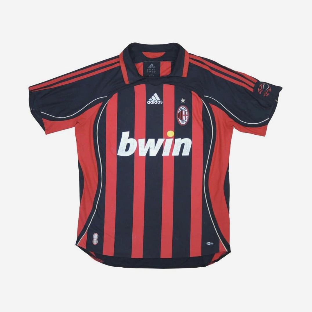 The Retro1999 AC Milan 2006-07 Home Shirt features classic black and red stripes, the bwin sponsor logo, Adidas branding, and the club crest. This retro kit includes short sleeves with red accents on the sides and shoulders.