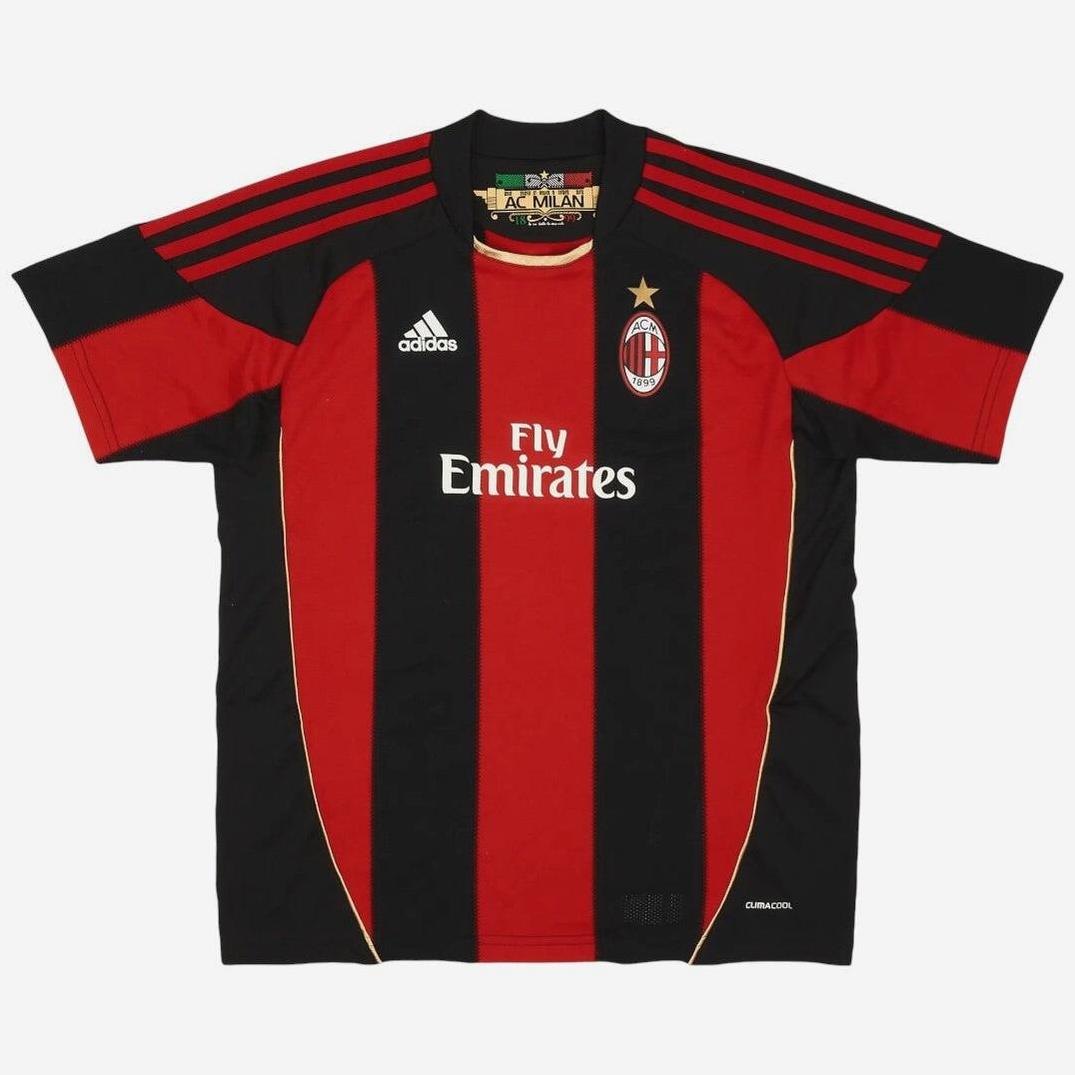 The Retro1999 AC Milan 2010-11 Home Shirt features black and red stripes, a gold star above the crest, Adidas logo, and Fly Emirates sponsor—capturing AC Milans classic style.