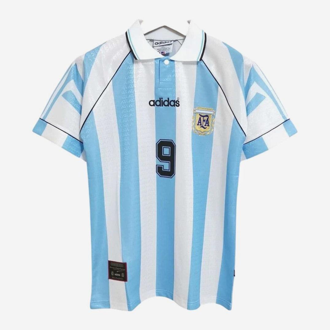 The Retro1999 Argentina 1994 Home Shirt features classic light blue and white stripes, number 9, AFA crest, and black adidas logo—a legendary retro kit perfect for any football jersey collection. Displayed on a hanger.