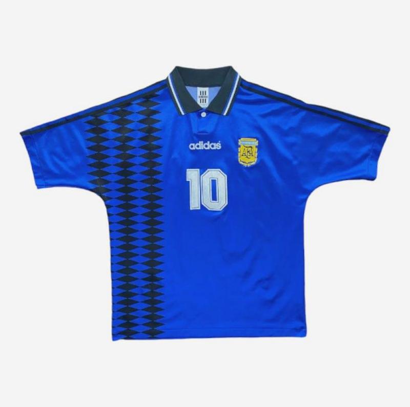 A blue Argentina Retro 1994 Away Shirt by Retro1999 features the number 10, black patterned stripes, a yellow crest, and a black collar with white trim—an iconic football piece from the World Cup 1994 era, shown on a white background.
