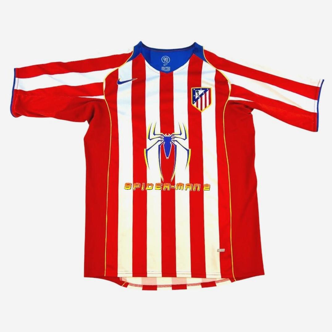 The Retro1999 Atletico Madrid 2004-05 Home Shirt features red and white stripes with blue accents, the club logo, a bold Spider-Man symbol, and SPIDER-MAN 2 text, inspired by classic designs and Columbia Pictures’ sponsorship.