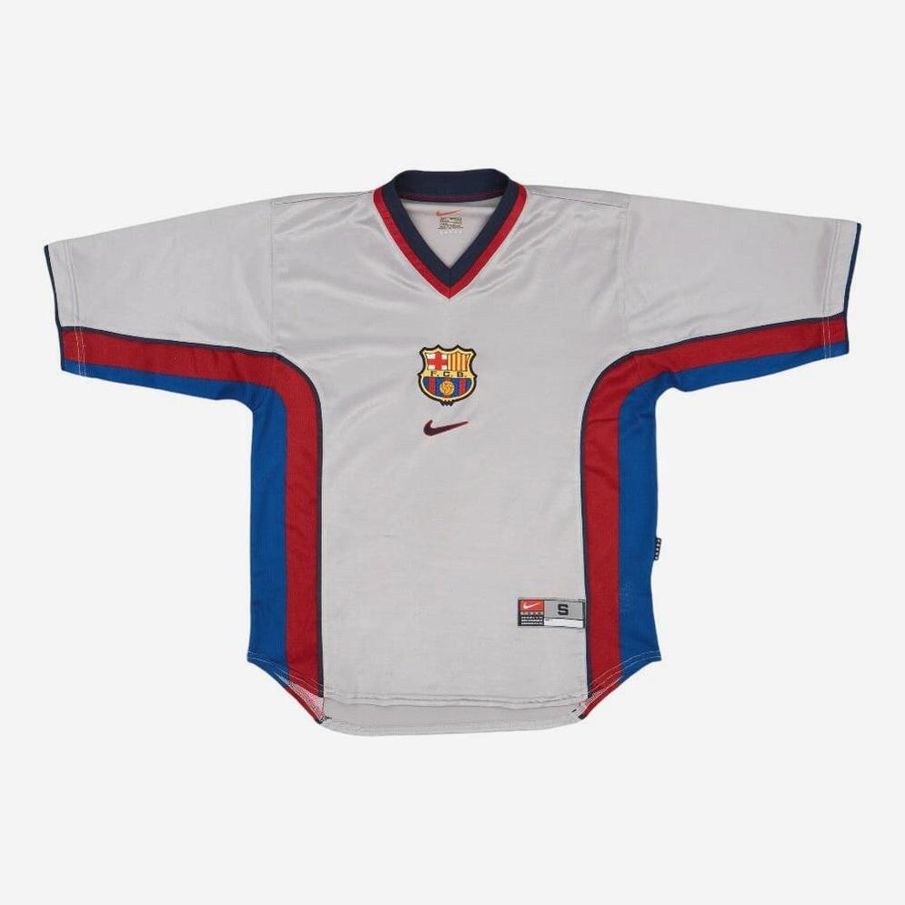 The Retro1999 Barcelona 1998-99 Away Shirt is a white soccer jersey with red and blue side panels, short sleeves, a red logo, and the club crest, inspired by FC Barcelona’s football heritage.