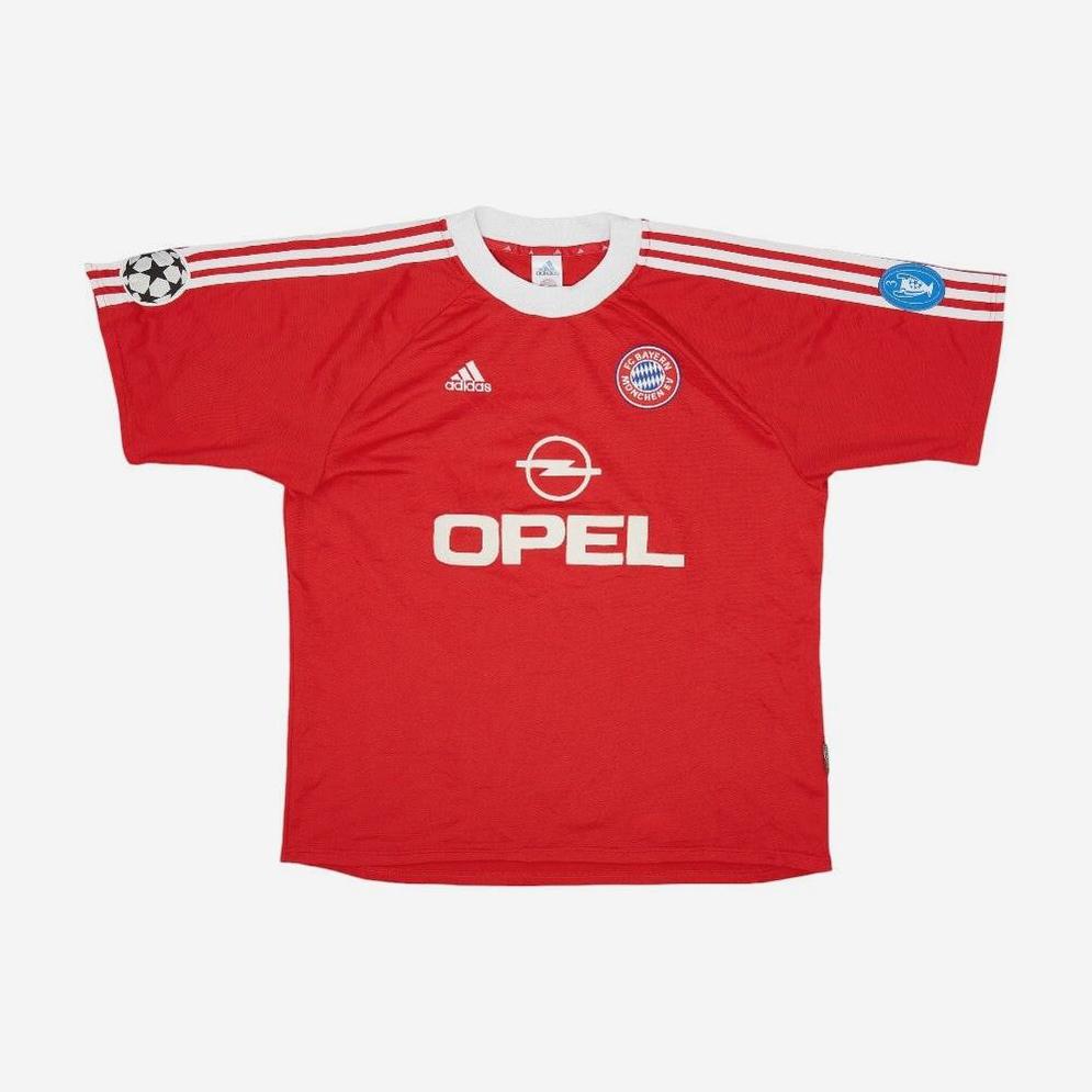 The Retro1999 Bayern Munich 2000-01 Home Shirt is a classic red kit with white shoulder stripes, Opel sponsor, club crest, Champions League patch on the right sleeve, and UEFA Respect patch on the left—perfect for Bundesliga fans.