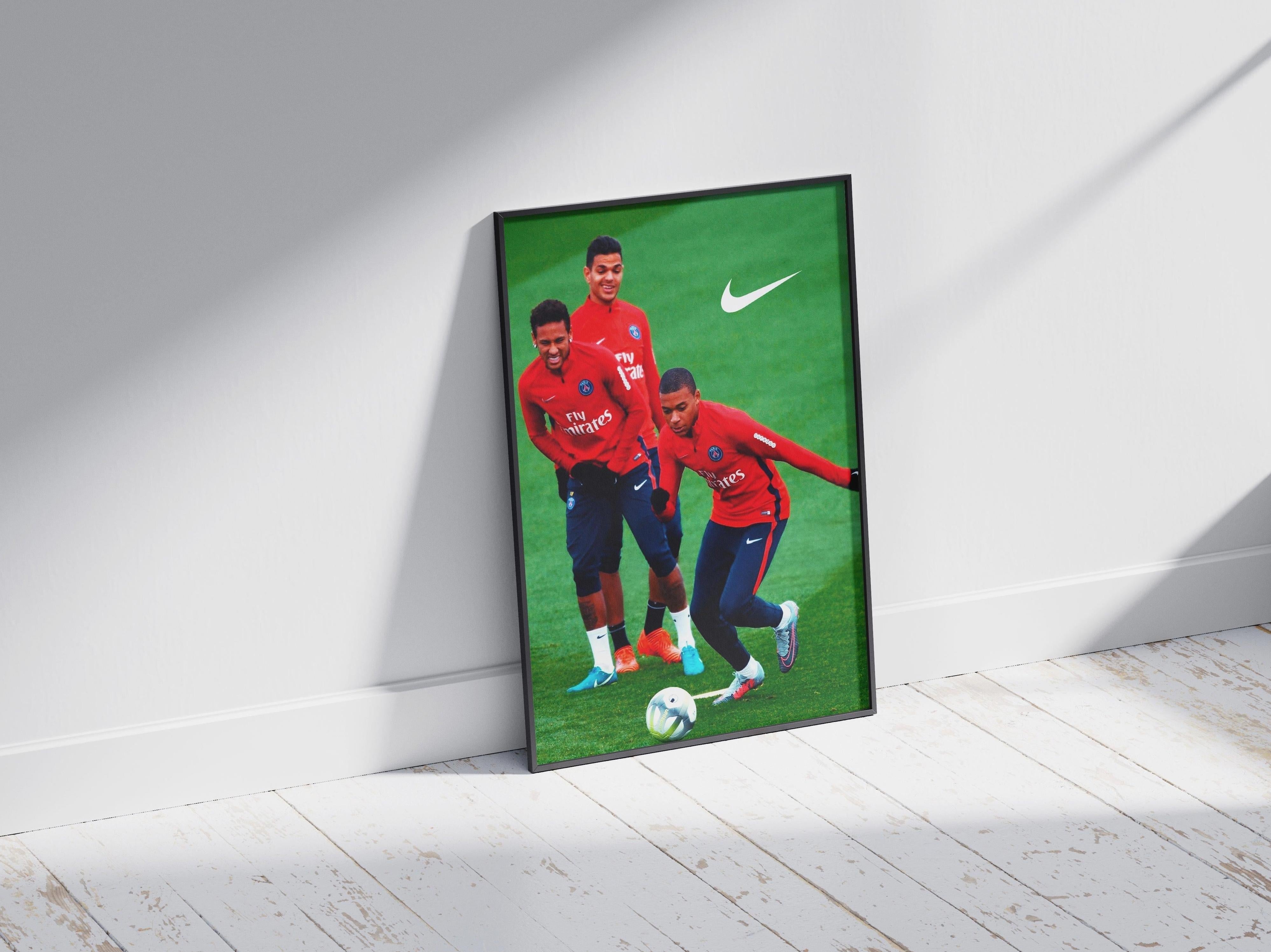 The Ben Arfa x Neymar x Mbappe Poster by Retro1999 shows the three players in red jerseys on a green field with a soccer ball. The framed print leans against a white wall, and the Nike logo appears in the top right corner.