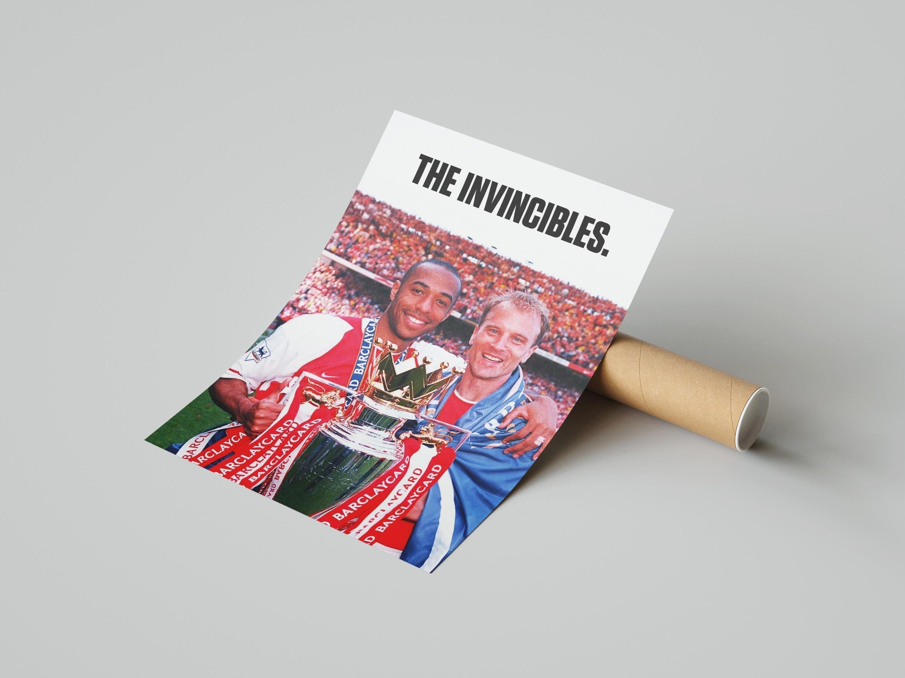 A partially rolled Bergkamp x Henry The Invincibles Poster by Retro1999 features two smiling footballers with the Premier League Trophy and THE INVINCIBLES text above, set against a stadium—a must-have for any Arsenal FC supporter.