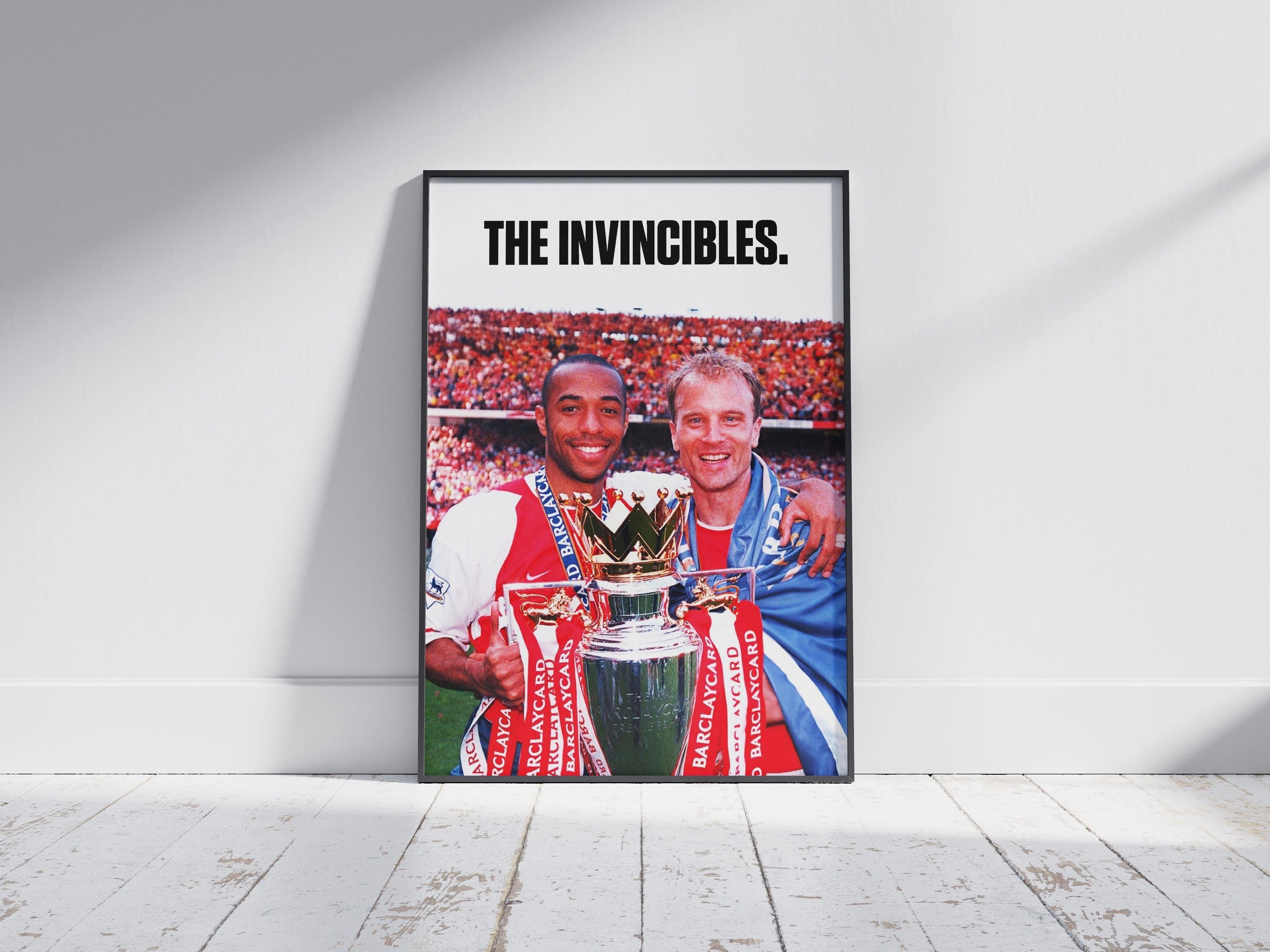 The Bergkamp x Henry The Invincibles Poster by Retro1999 features two smiling Arsenal legends in kit, celebrating with the Premier League Trophy, bold text reading THE INVINCIBLES above, and a cheering stadium crowd behind.