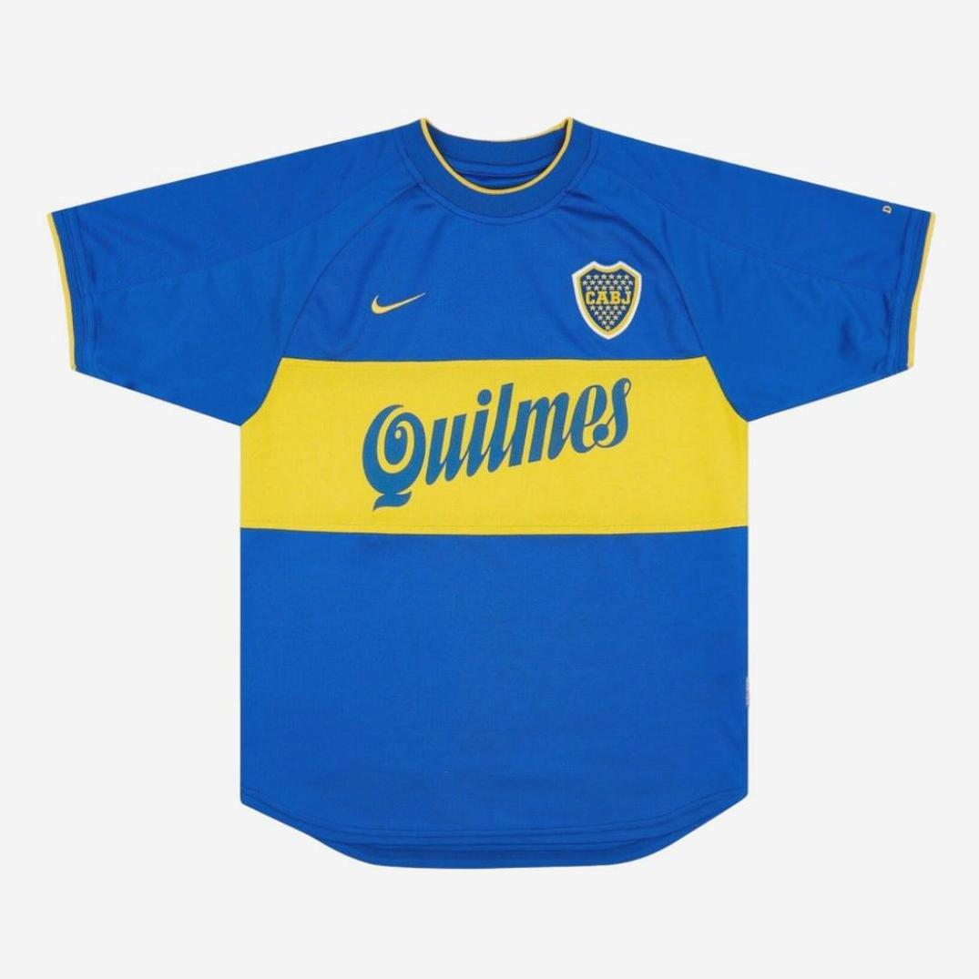 The Boca Juniors 1999-00 Home Shirt by Retro1999 features the iconic blue and yellow design with a wide horizontal stripe, club crest, and Quilmes sponsor—an essential for any football memorabilia collection.