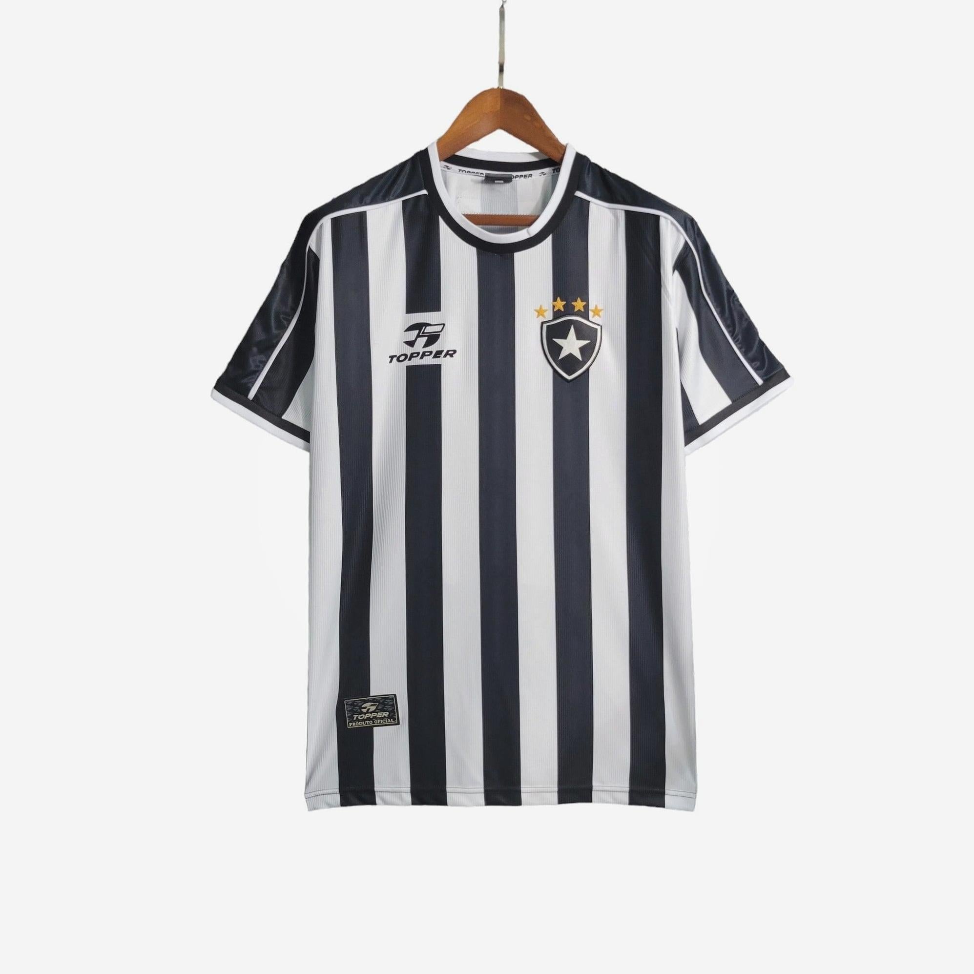 The Botafogo 1999-00 Home Shirt by Retro1999 features black and white vertical stripes, a retro design with a crest topped by four gold stars, and the Topper logo, displayed on a wooden hanger against a white background.