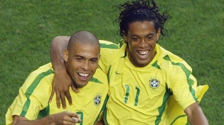 Two Brazilian players in yellow Retro1999 Brazil 2002 Home Shirts celebrate on the field, smiling with arms around each other—a classic football moment in this iconic jersey.