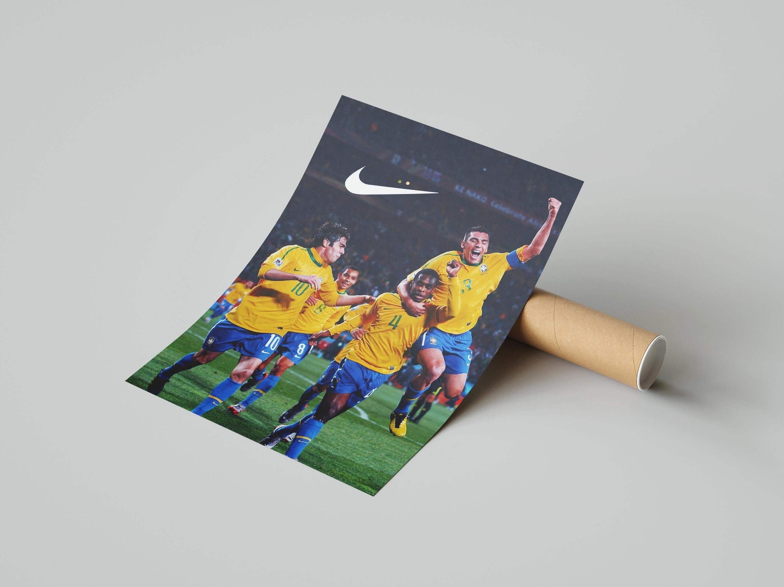The Brazil 2010 World Cup Poster by Retro1999 shows three Brazilian footballers in yellow jerseys celebrating, with a white Nike logo above them. The partially unrolled poster rests on a light gray surface with its cardboard tube.