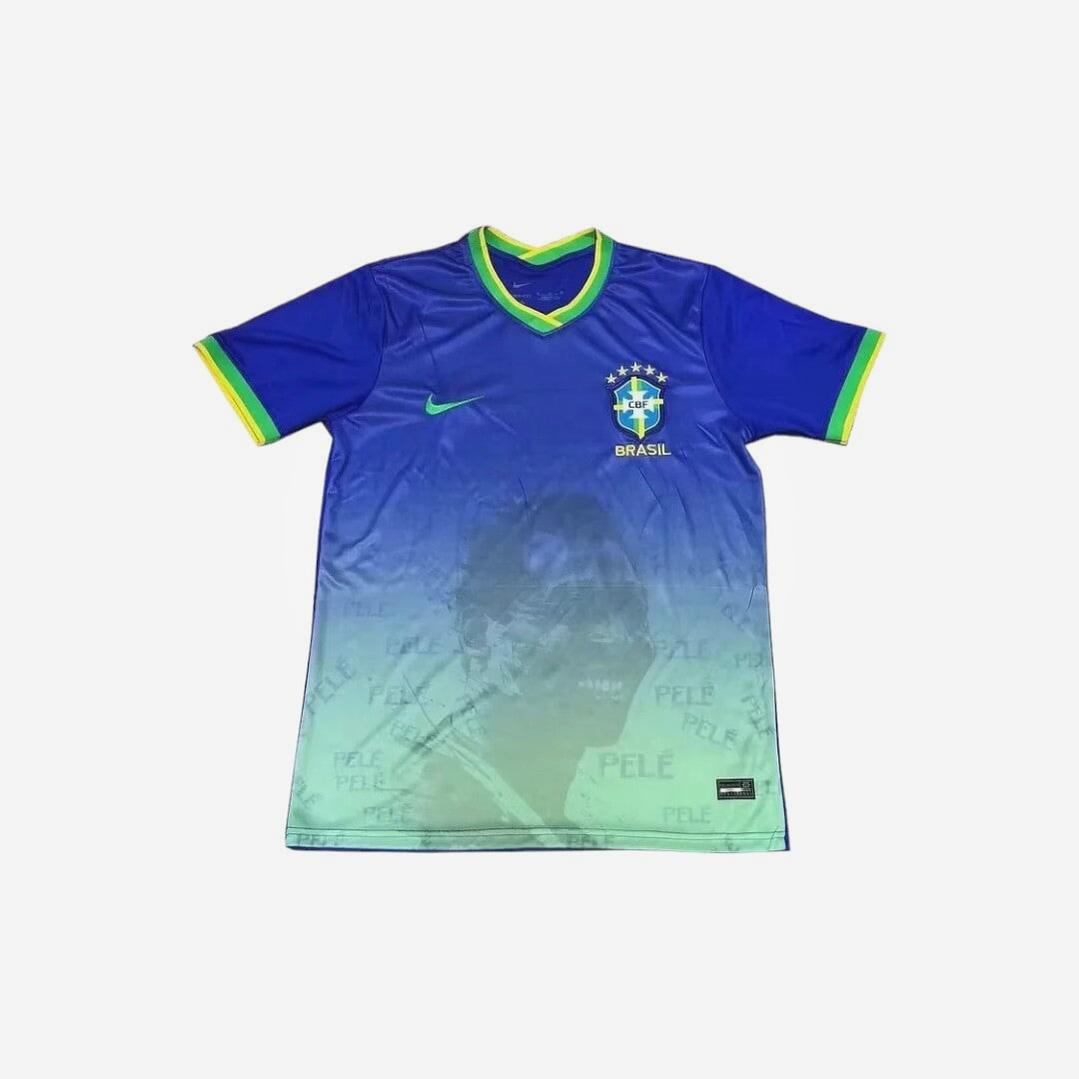 The Retro1999 Brazil 2022/2023 Pelé Special Commemorative Edition Shirt features blue and green colors, yellow trim, team crest, and a faded Pelé image with his name repeated on the lower half for a retro look.