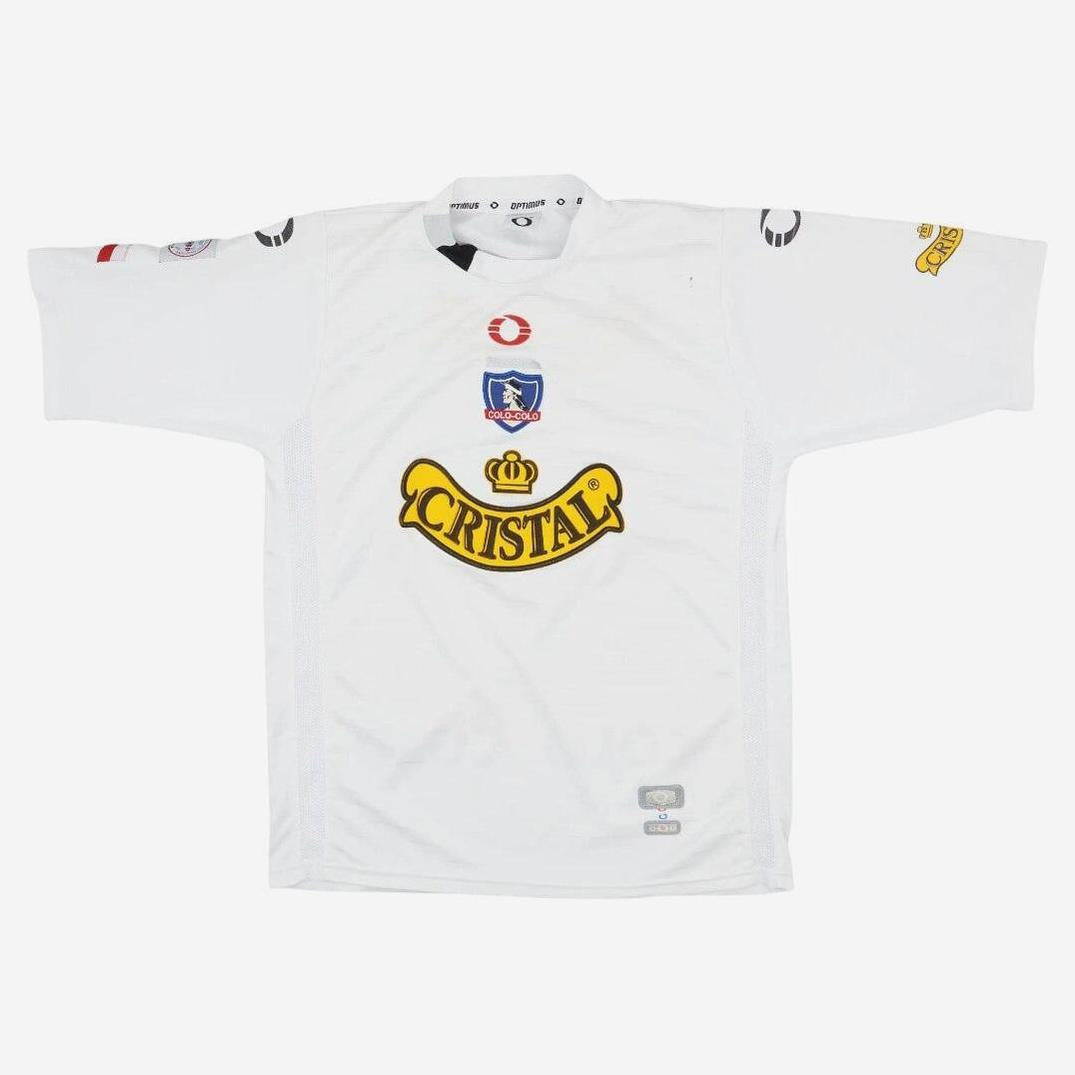 The Retro1999 Colo Colo 2004 Home Shirt is a white, short-sleeved nostalgic jersey with the Cristal logo in yellow, a blue and red Colo-Colo crest, plus multiple smaller sponsor logos on the sleeves and shoulders.