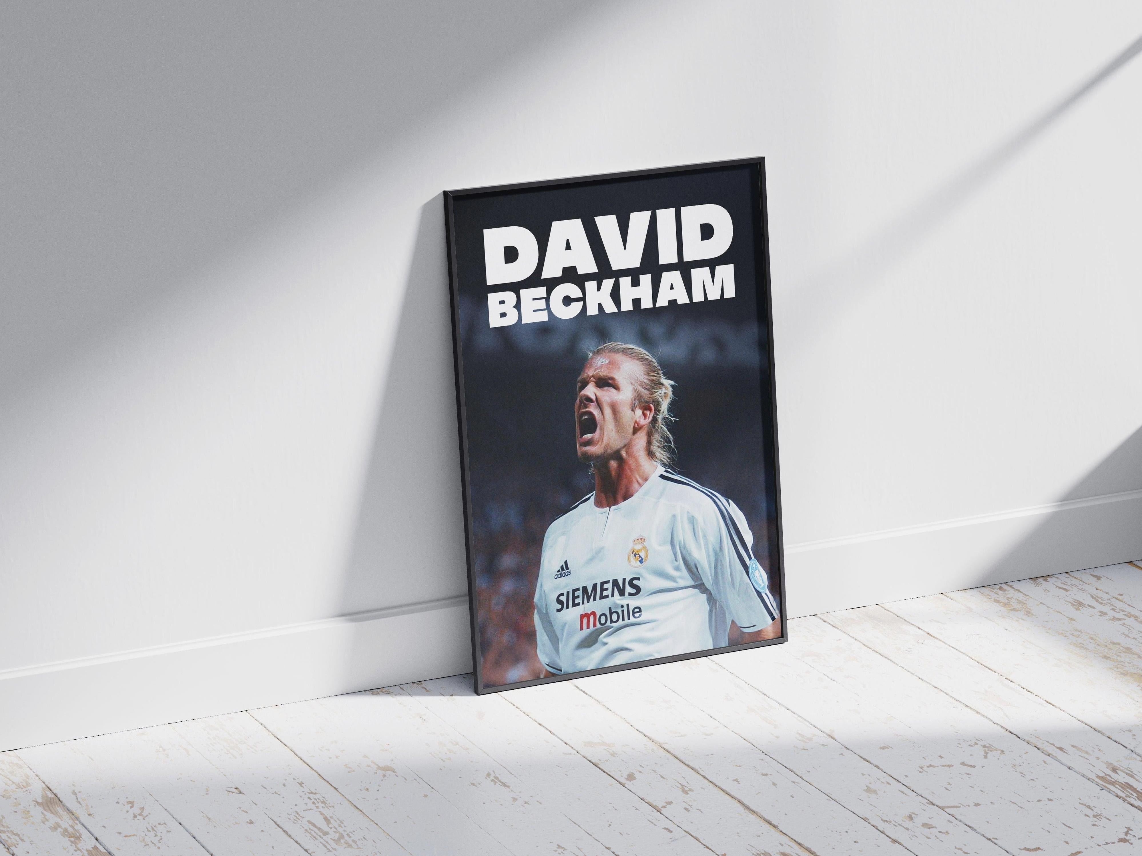 The Retro1999 David Beckham x Real Madrid Poster, displayed on a white wooden floor, features Beckham in his iconic jersey. Sunlight adds depth, making this poster a bold homage to football history and Real Madrid fans.