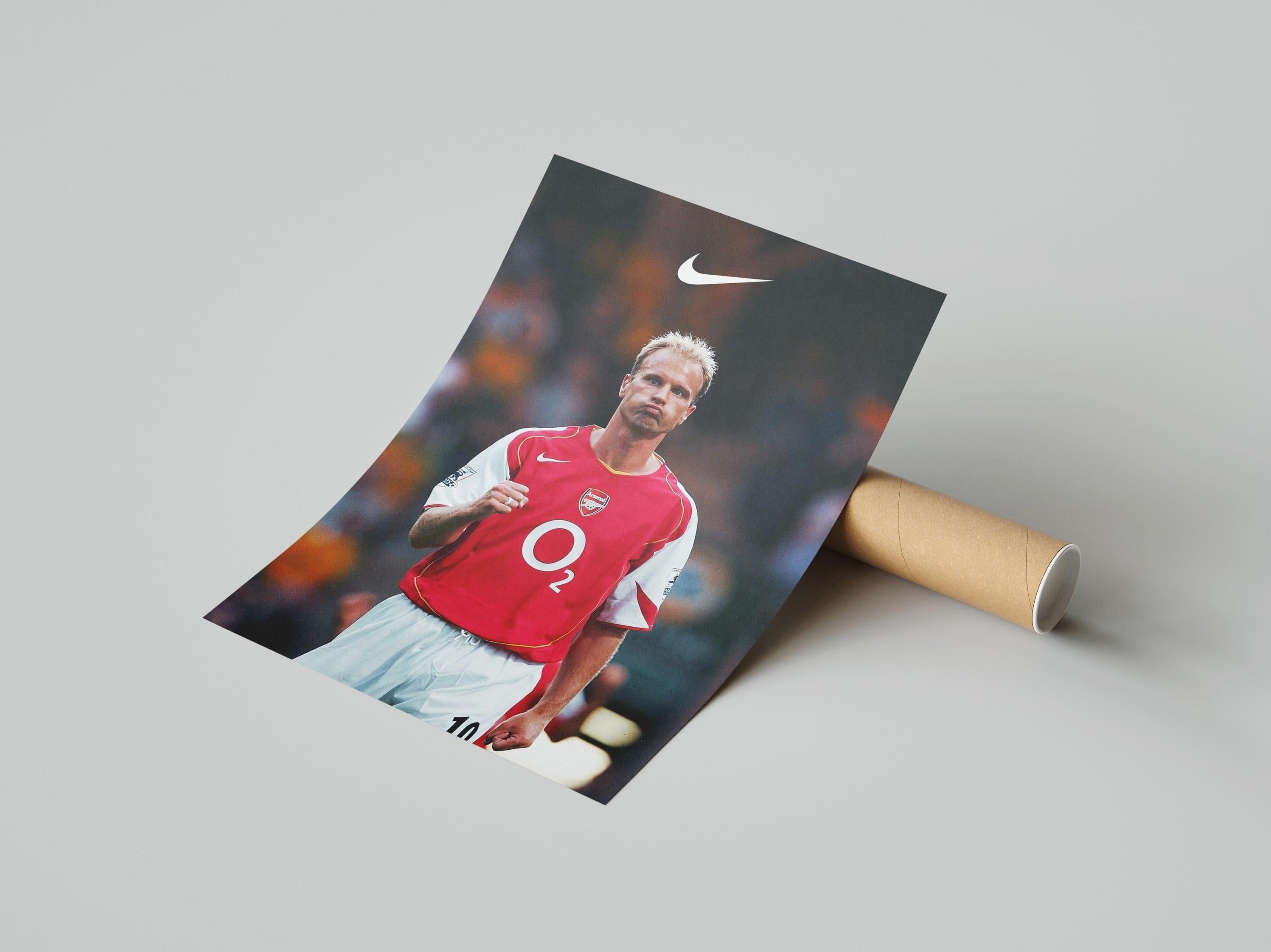 The Dennis Bergkamp x Arsenal Poster by Retro1999 shows the iconic legend in an O2-sponsored kit with Nike logo, standing on the field—a must-have collectible for devoted Arsenal fans.