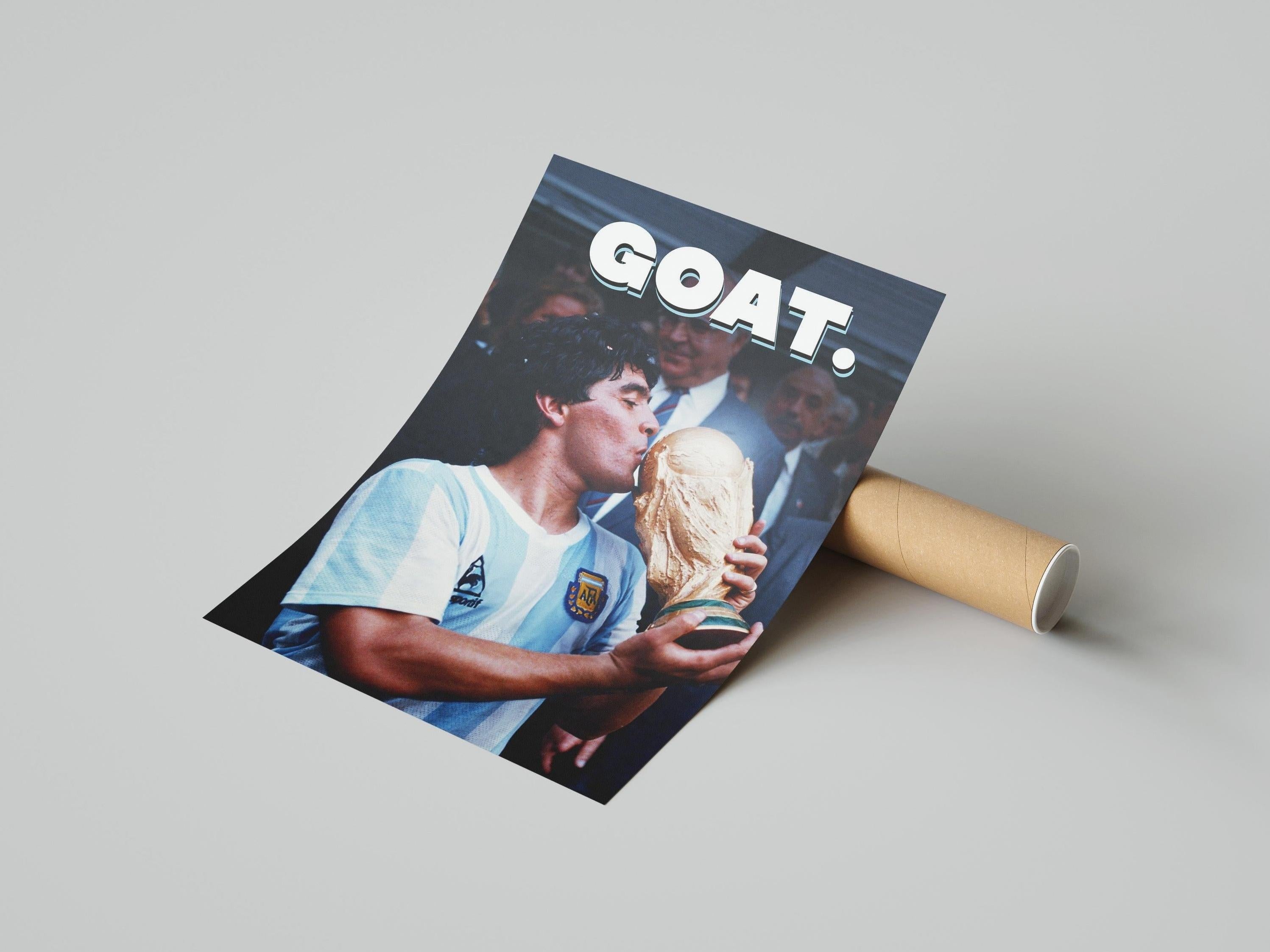 The Diego Maradona GOAT Poster by Retro1999 shows Maradona in an Argentina jersey kissing the 1986 FIFA World Cup, with GOAT. in bold at the top. The tribute poster comes partly rolled beside a cardboard tube.