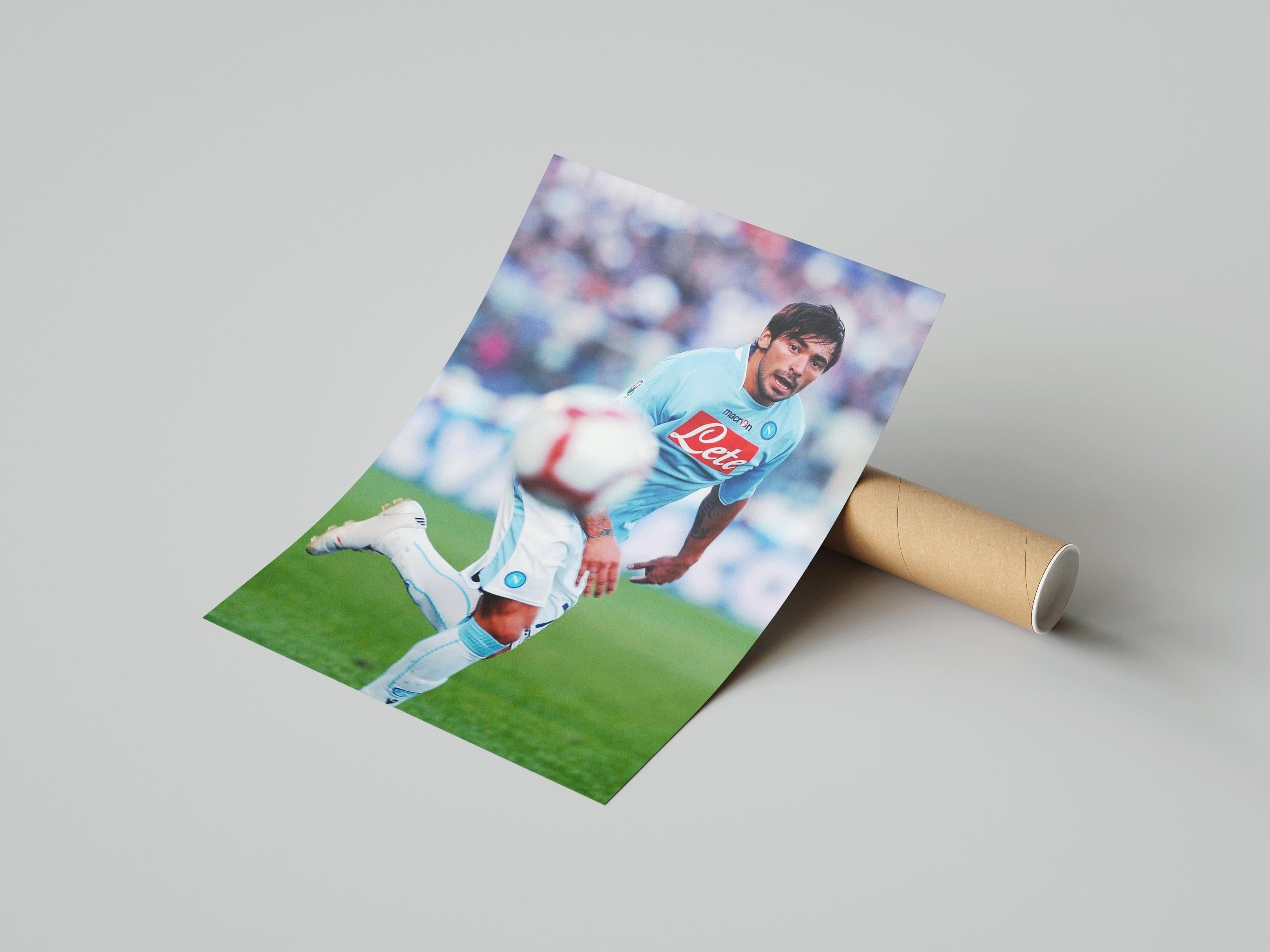 The Retro1999 Ezequiel Lavezzi x SSC Napoli Poster shows Lavezzi in a light blue kit sprinting during a Serie A match, with a blurred soccer ball and stadium crowd in the background. Poster comes rolled up for easy delivery.