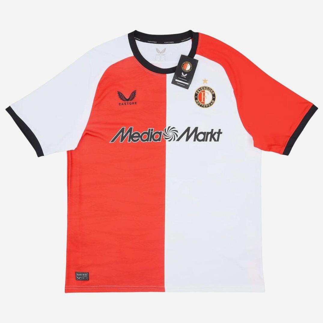 The Feyenoord 2024-25 Home Shirt by Retro1999 features red and white colors, black trim, MediaMarkt sponsor, club crest with gold star, Castore logo on the chest, premium fabric, and comes with tags attached. Photographed on a white background.