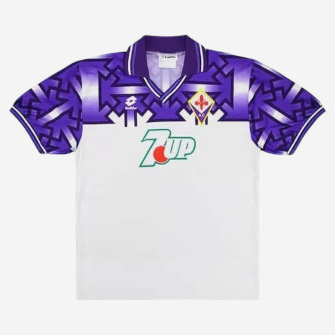 The Fiorentina 1992-93 Away Shirt by Retro1999 is a classic white kit with purple geometric patterns, 7UP sponsor, club badge on the left chest, and Lotto logo on the right—a retro Serie A favorite.