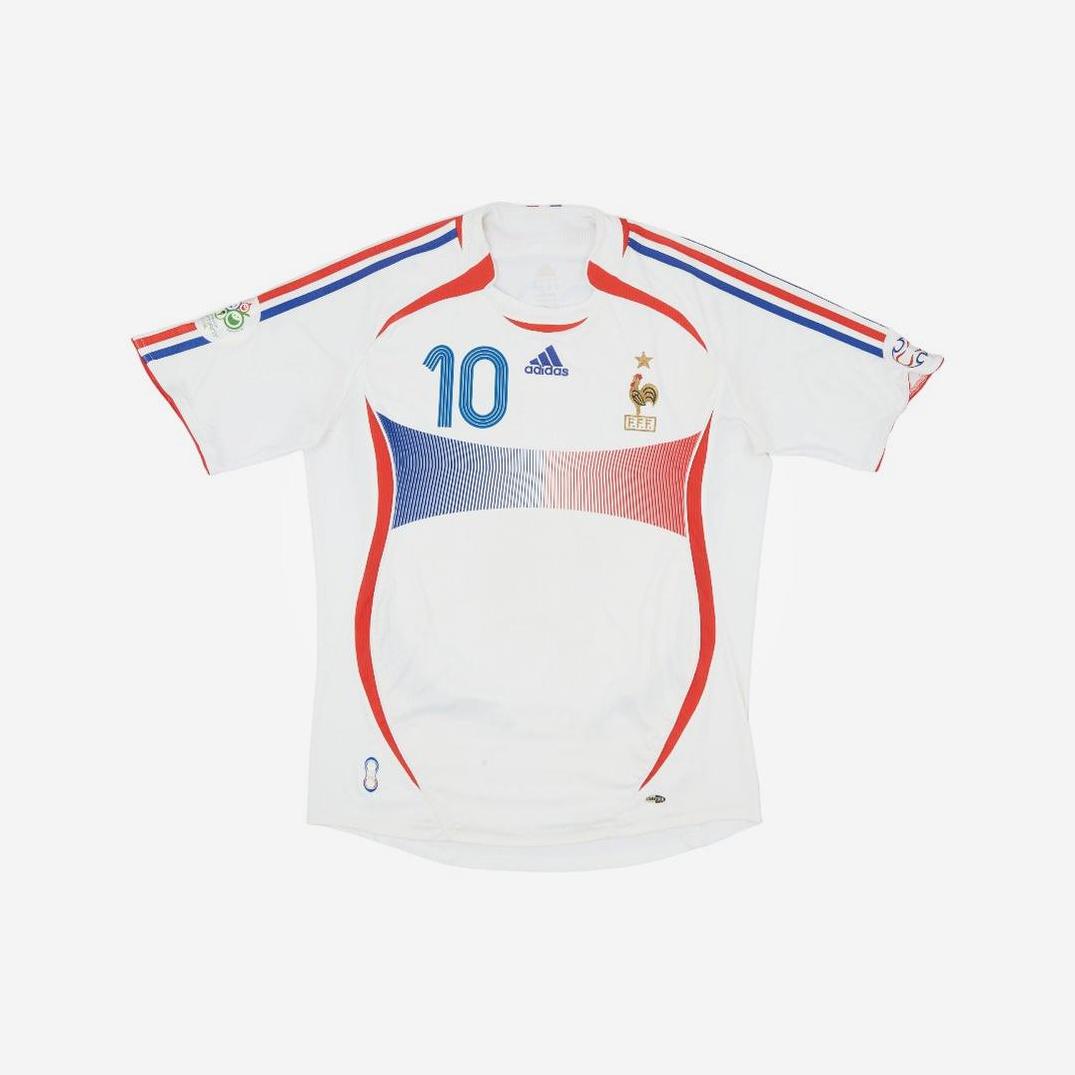 The France 2006 Away Shirt by Retro1999 is a classic white kit with red and blue accents, number 10, chest badge, Adidas logo, and tournament patches—a must-have piece of football history.
