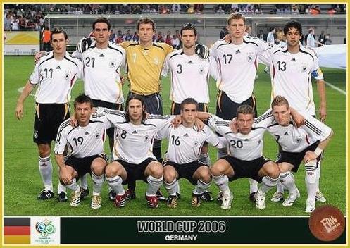 The German national soccer team poses for a group photo in their Retro1999 Germany 2006 Home Shirt before a 2006 FIFA World Cup match, with eleven players arranged in two rows and the stadium crowd behind them.