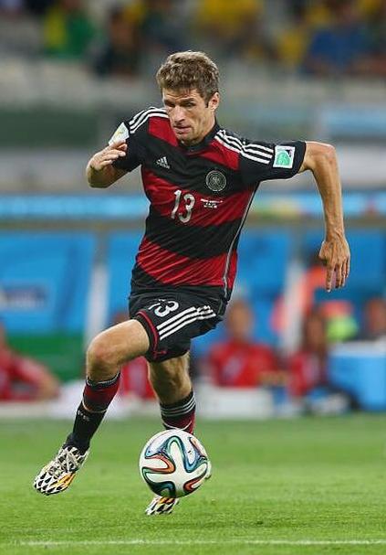 A soccer player in a Retro1999 Germany 2014 Away Shirt with number 13 is dribbling a ball on a green field during a match.