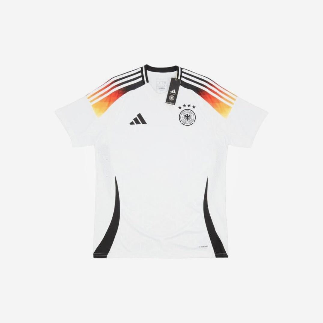 The Germany 2024 Home Shirt by Retro1999 features white fabric, four stars, team crest, and shoulder stripes in black, red, and yellow—a retro kit that showcases the German flag’s colors.