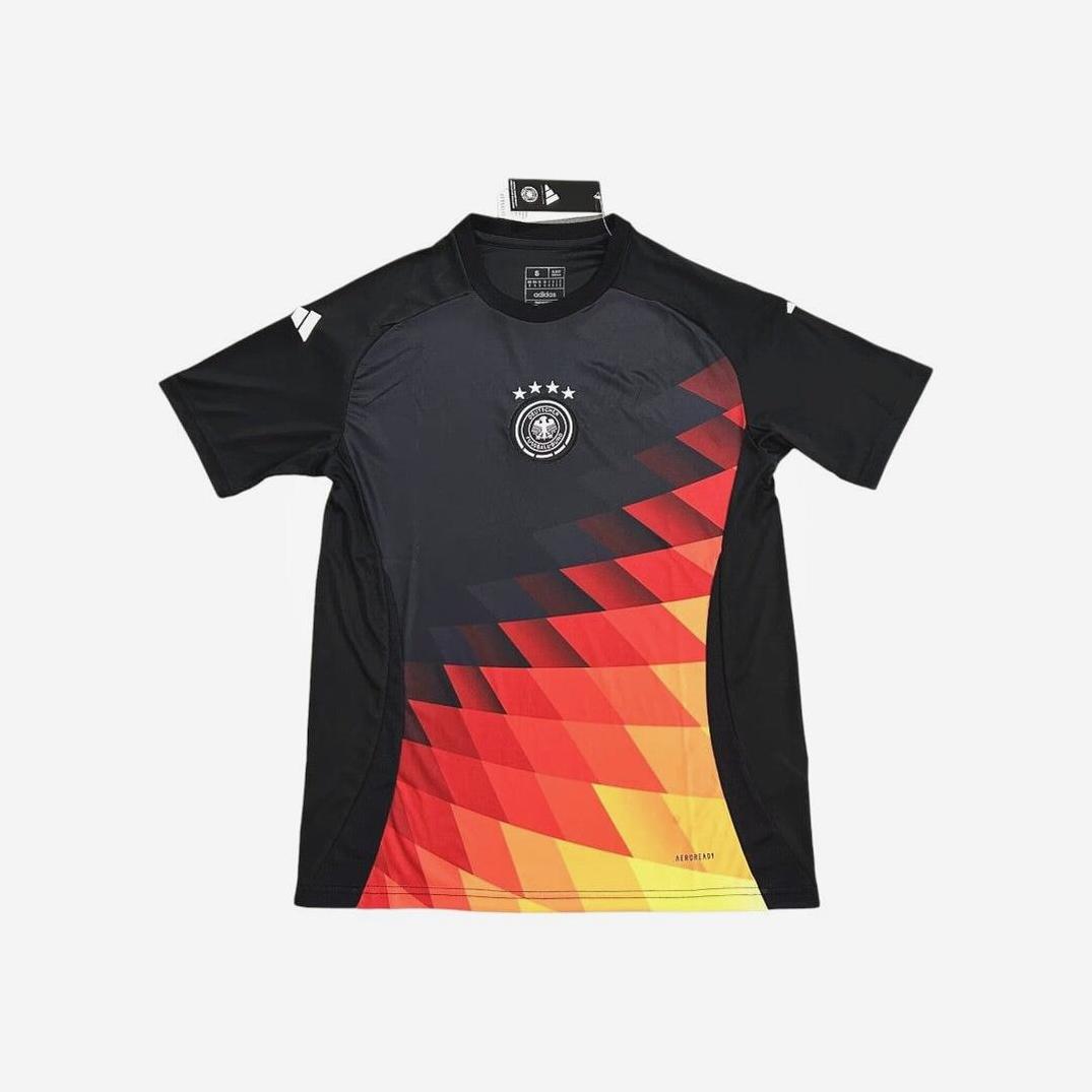 The Retro1999 Germany 2024 Pre-Match Shirt features a black short-sleeve design with red, orange, and yellow geometric patterns and the German team crest with four stars. The jersey is displayed flat on a white background.