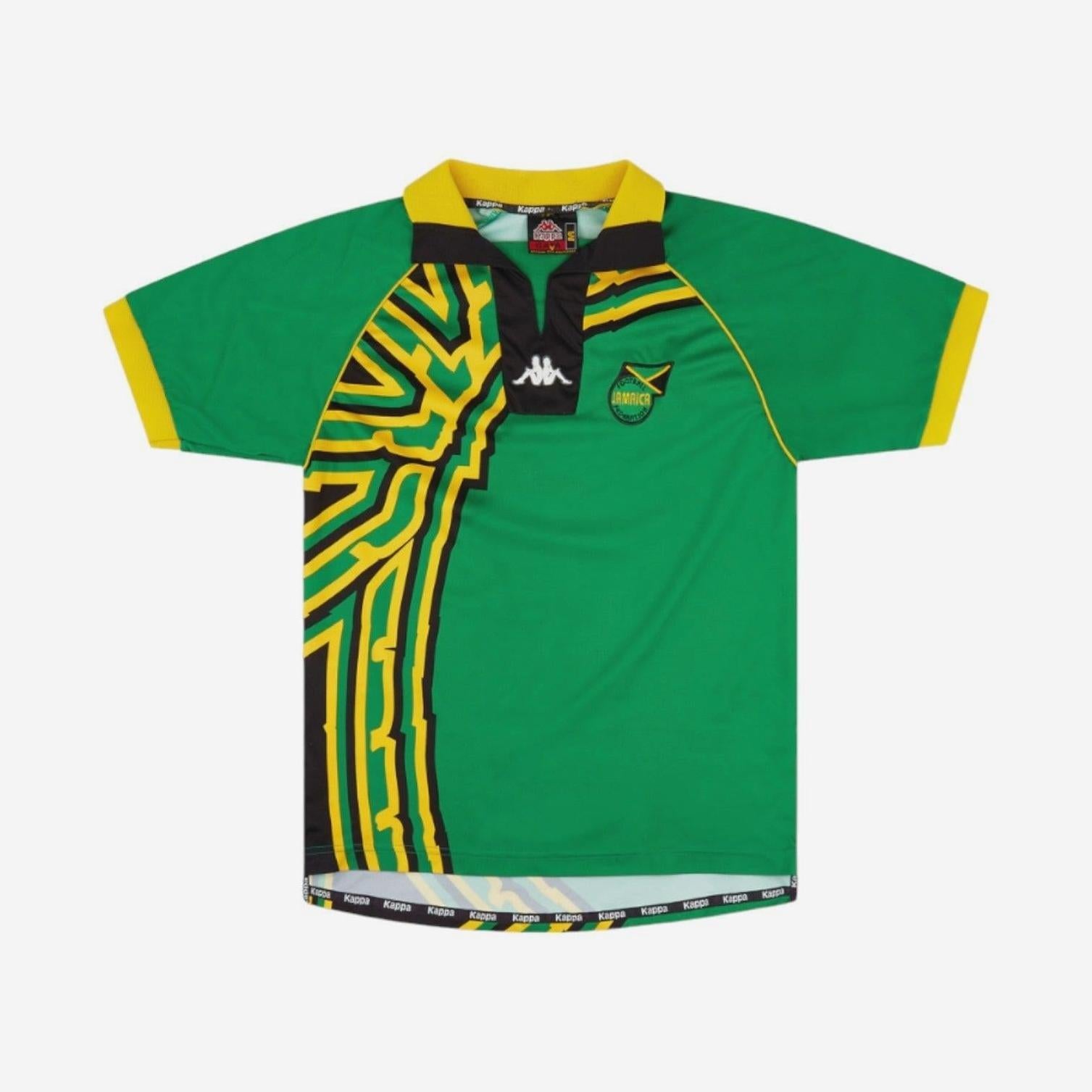 The Jamaica 1998 Away Shirt by Retro1999 features green short sleeves, yellow and black geometric patterns, yellow cuffs and collar trim, Kappa logo, and crest patch—paying tribute to the iconic Reggae Boyz kit inspired by the Jamaican flag.