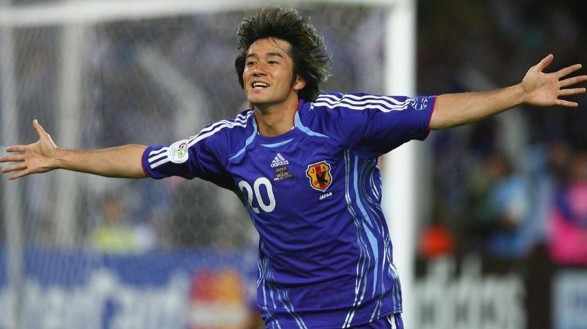 A soccer player in the Retro1999 Japan 2006 Home Shirt, number 20, celebrates with arms outstretched on the field during a match—a classic moment in Japanese football history.