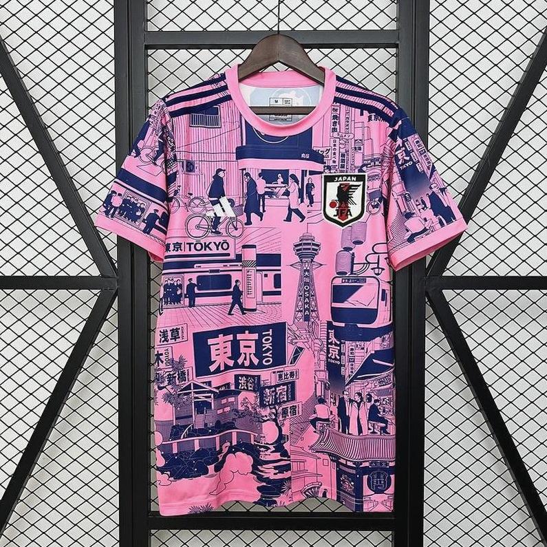 The Retro1999 Japan 2024 Special Edition Shirt, in pink and navy with Tokyo-inspired illustrations and the national team crest on the chest, hangs on a black grid wall.