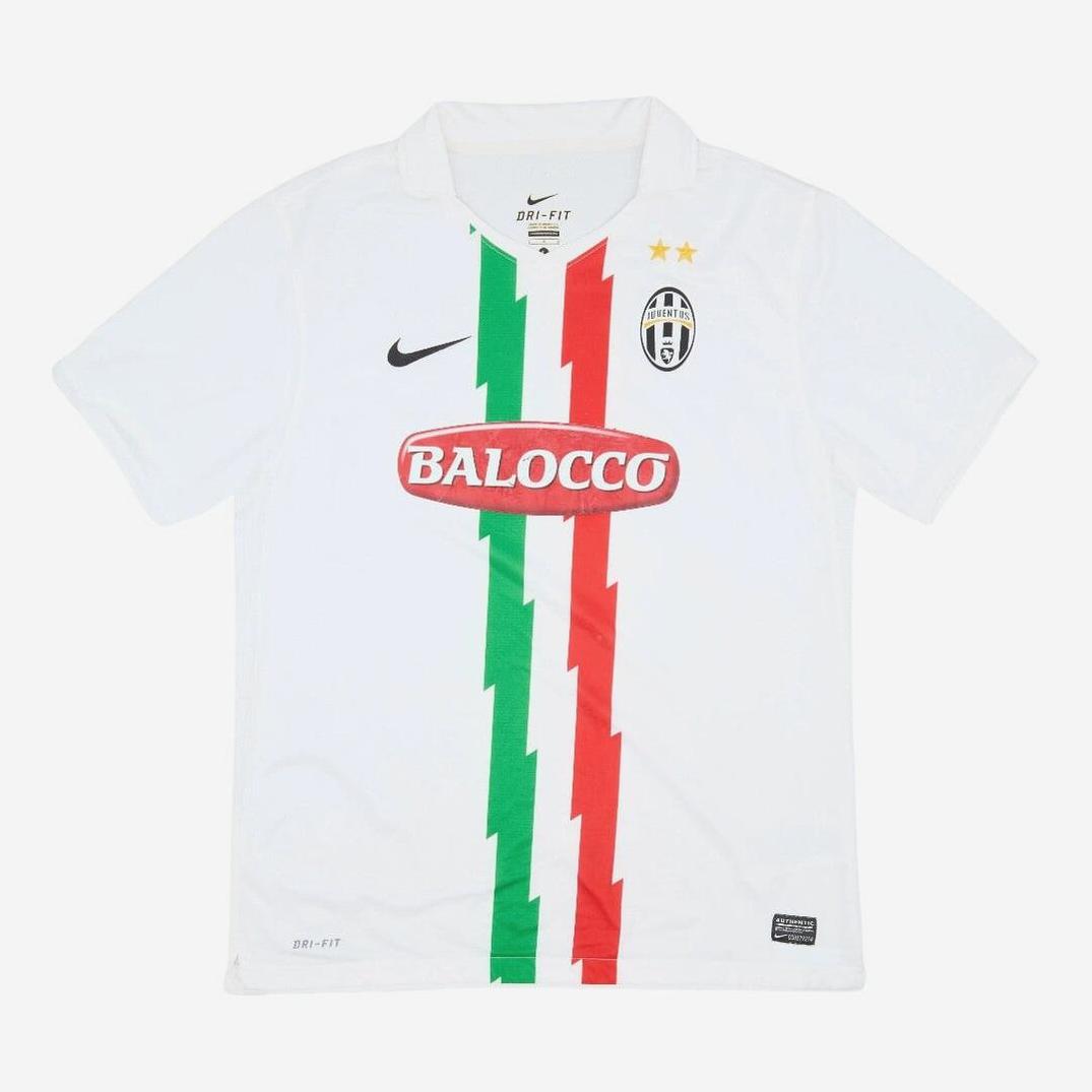 The Retro1999 Juventus 2010-12 Away Shirt is a white kit with green, white, and red zigzag stripes, Nike logo, two gold stars, Juventus badge, and Balocco sponsor—ideal for Serie A fans.