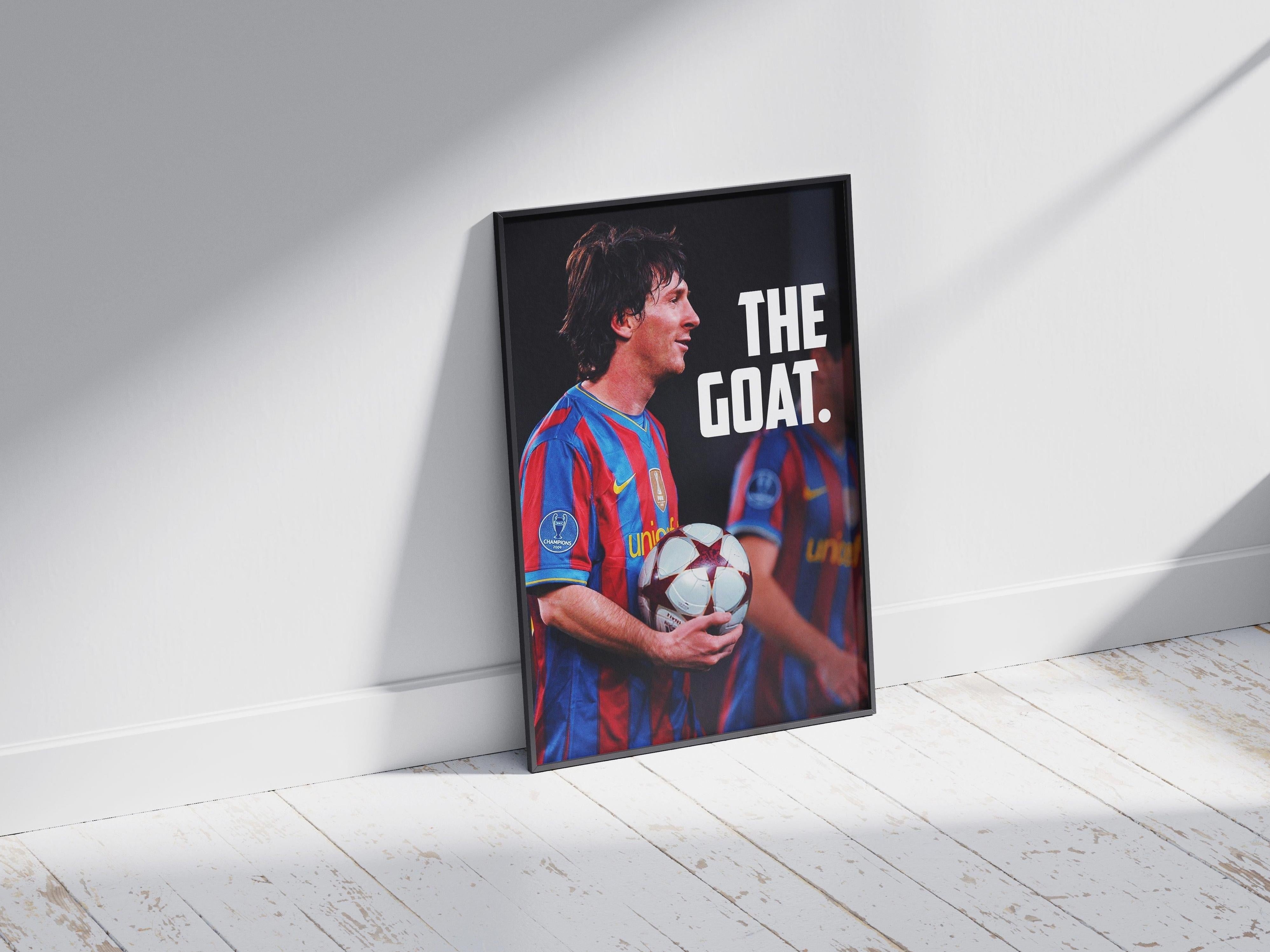 The Retro1999 Lionel Messi MOTM Poster features the legend in a red and blue striped jersey, holding a ball with THE GOAT. in bold white text, framed and leaning against a sunlit wall on wooden flooring—perfect for collectors.