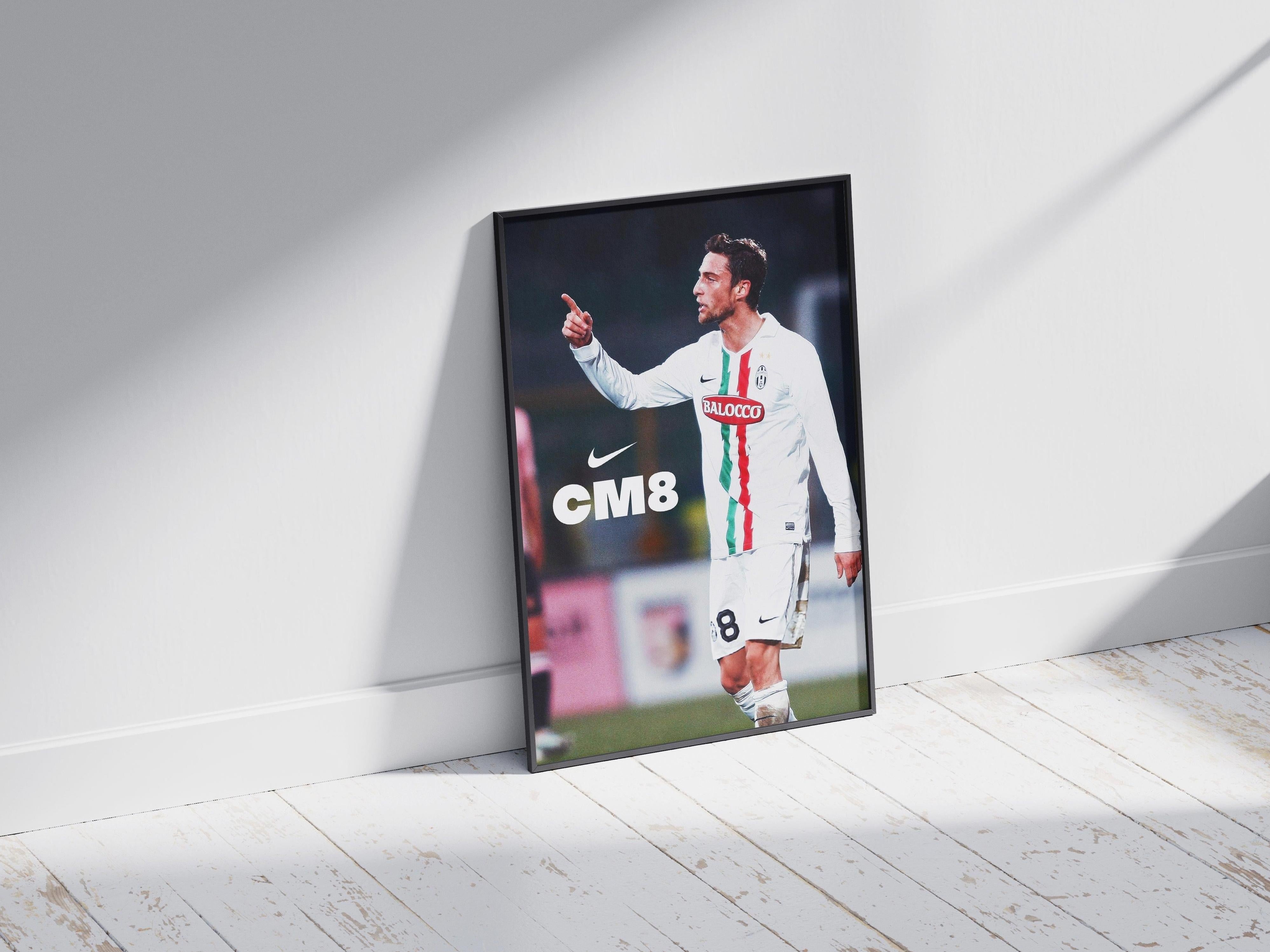 The Marchisio CM8 Poster by Retro1999 features the Juventus star in a white kit with green and red stripes, pointing and smiling on a white wooden floor—an ideal piece for any football enthusiast.