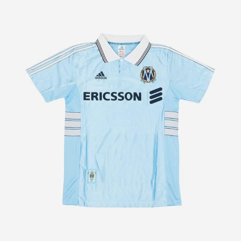 The Retro1999 Marseille 1998-99 Away Shirt features a light blue design with white and black accents, Ericsson sponsor text, and the club crest—a classic pick for fans who appreciate retro Ligue 1 jerseys.