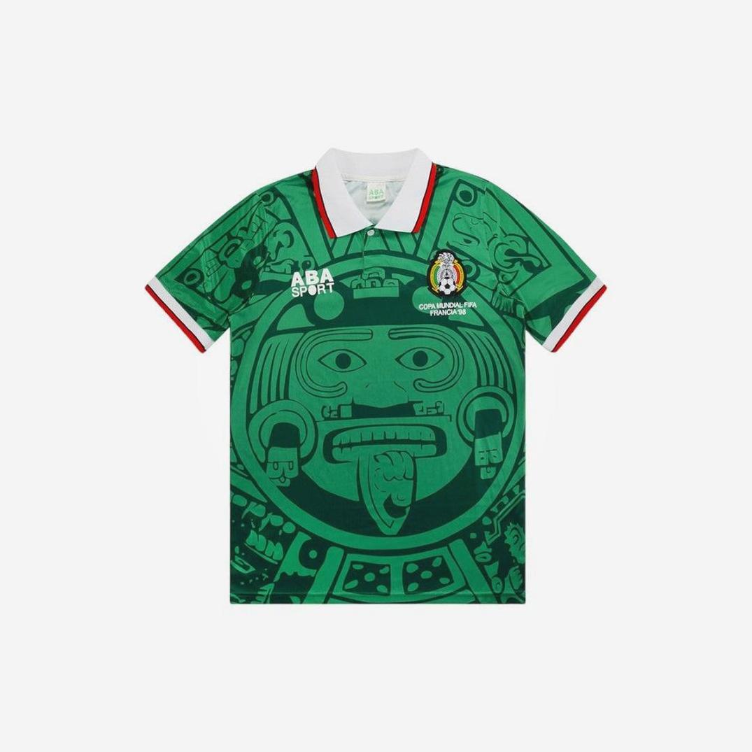 The Retro1999 Mexico 1998 Home Shirt features a green design with a white collar, red-trimmed sleeves, an Aztec calendar print, and the national team crest—a true standout among retro football kits.
