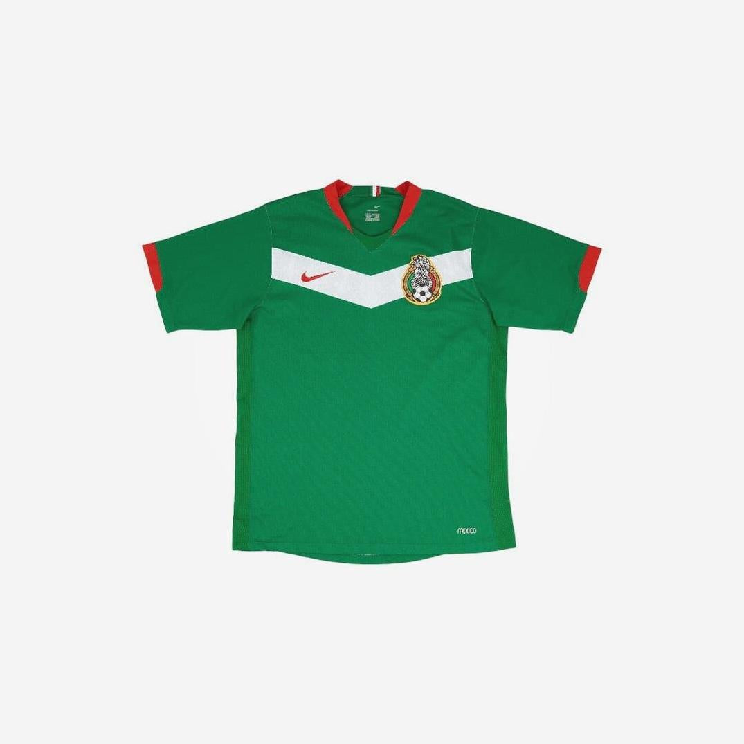 The Retro1999 Mexico 2006 Home Shirt is a green short-sleeved jersey with red and white accents, capturing the classic style of the Mexico National Team’s iconic kit—perfect for retro football fans.