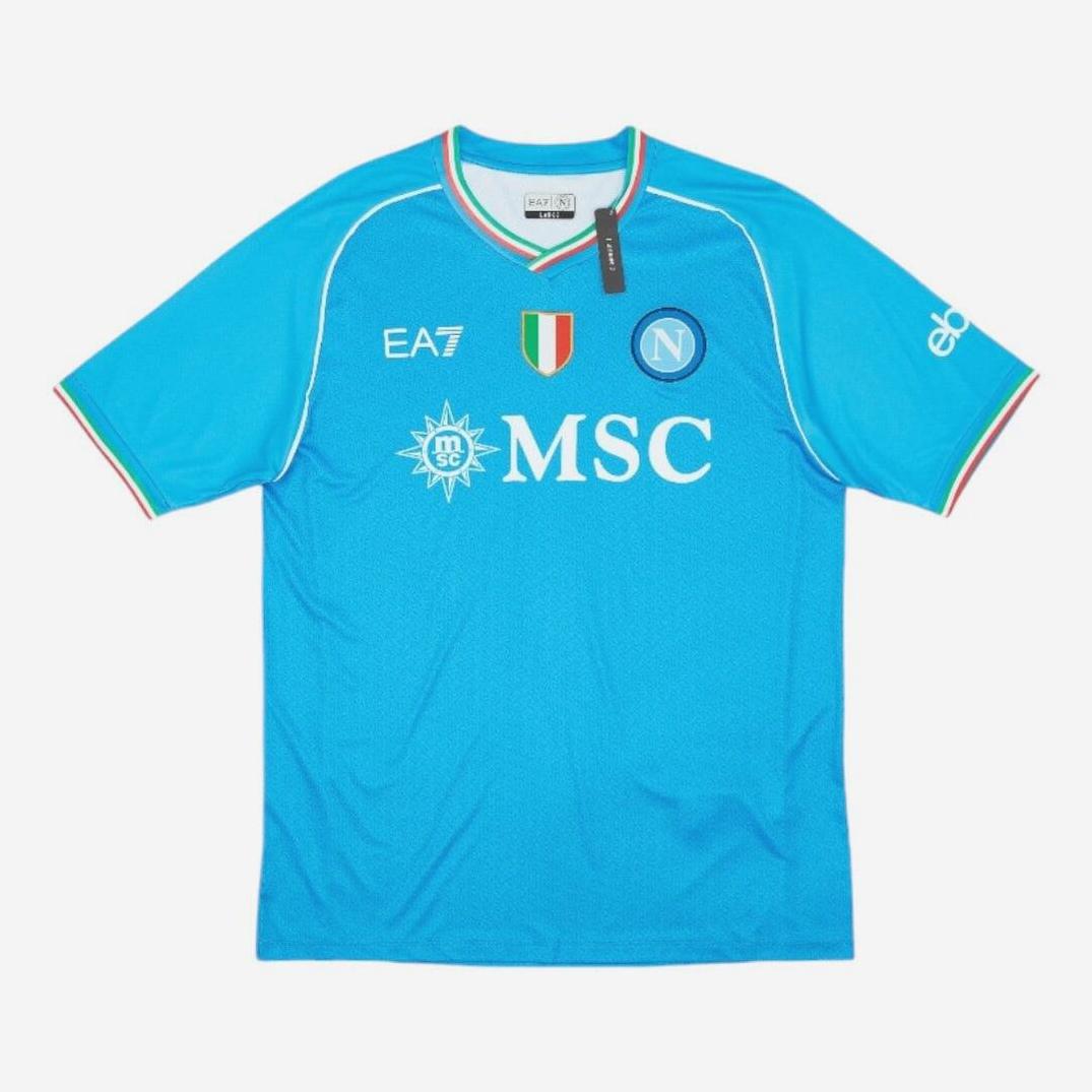 The Retro1999 Napoli 2023-24 Home Shirt features a blue design with EA7 logo, Italian flag badge, Napoli crest, MSC sponsor, and red-white-green trim on the sleeves—a must-have retro kit for dedicated fans.
