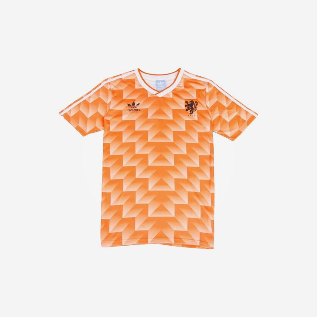 The Retro1999 Netherlands 1988 Home Shirt is an orange short-sleeve soccer jersey with a geometric pattern, white shoulder stripes, Adidas logo on the right chest, and a lion crest on the left chest.