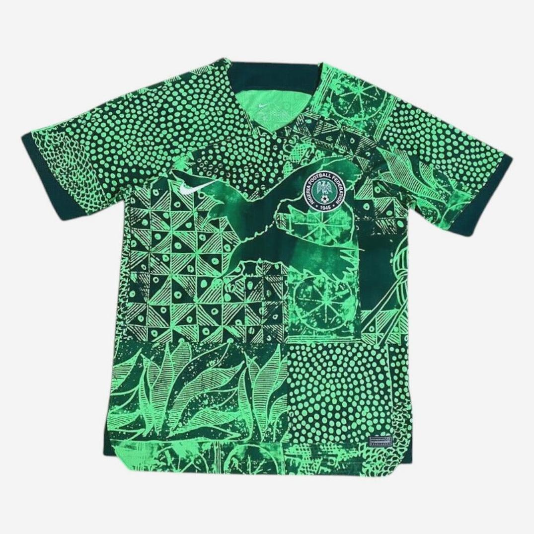 The Retro1999 Nigeria 2022 Home Shirt features a vibrant green and black pattern with geometric shapes, leaf designs, an eagle motif, and the Nigerian national football team badge on the chest.