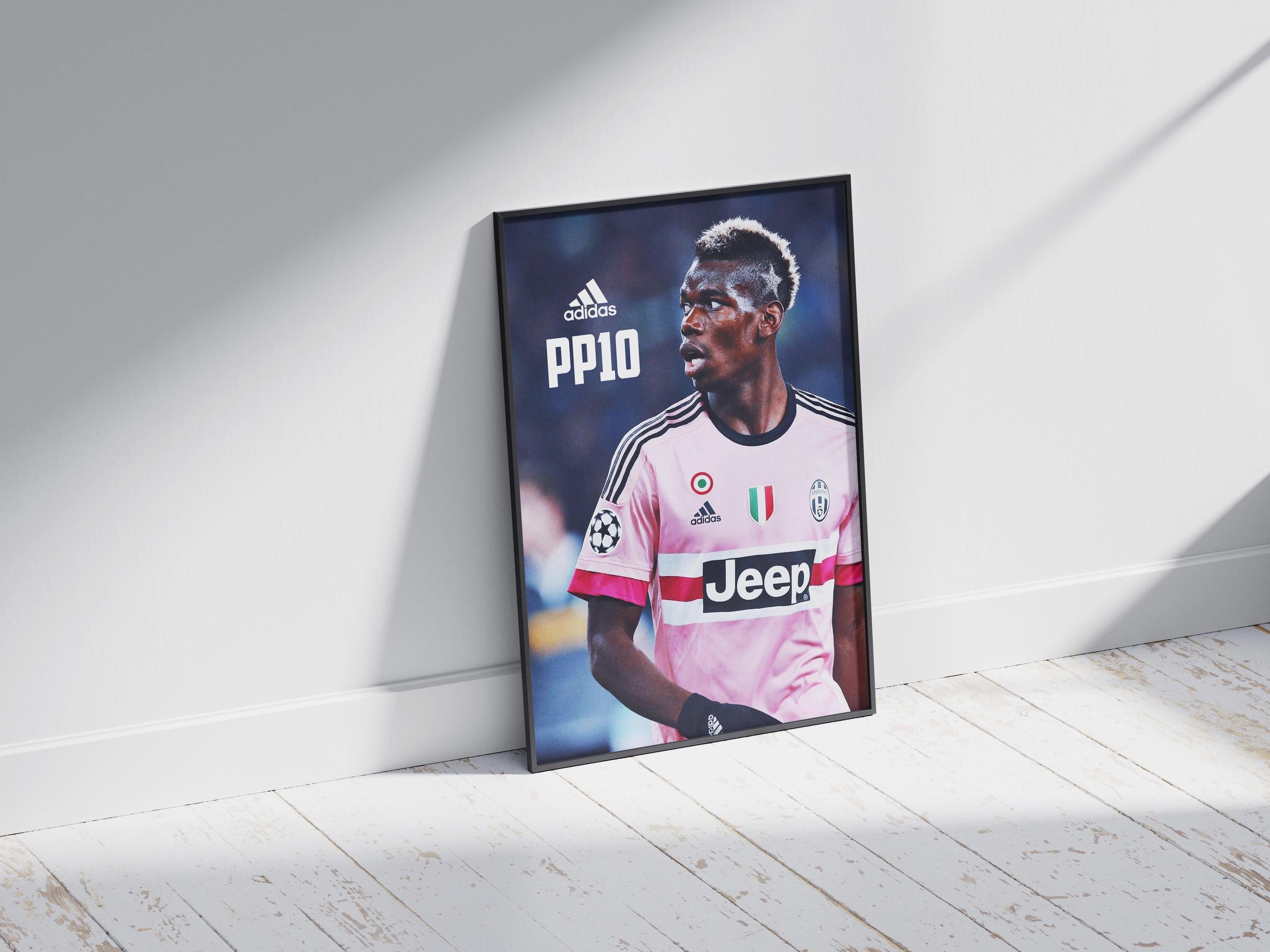 A Retro1999 Paul Pogba PP10 Poster shows him in a pink Juventus jersey with Adidas and Jeep logos, leaning against a white wall on a wooden floor—ideal football fan decor for UEFA Champions League lovers.