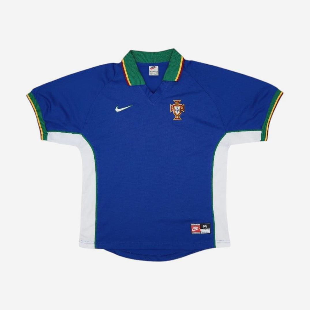 The Portugal 1997-98 Away Shirt by Retro1999 is a blue short-sleeve kit with white side panels, green trim, and yellow accents. It features the national team crest, a white Nike logo on the chest, and a red Nike tag near the hem.