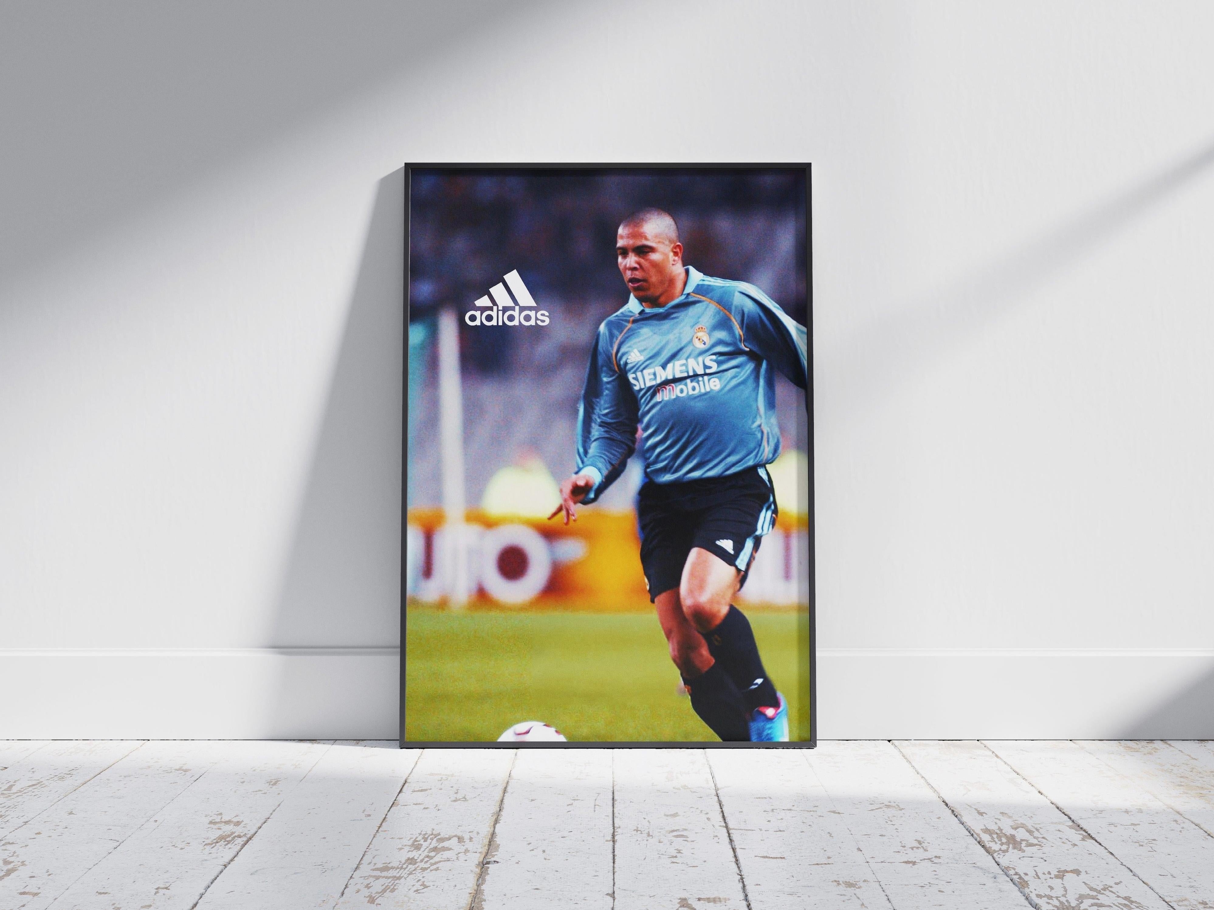 The Retro1999 R9 x Real Madrid Poster features Ronaldo dribbling in a blue jersey with visible Adidas and Siemens Mobile logos, propped against a white wall—ideal for football fans and collectors.