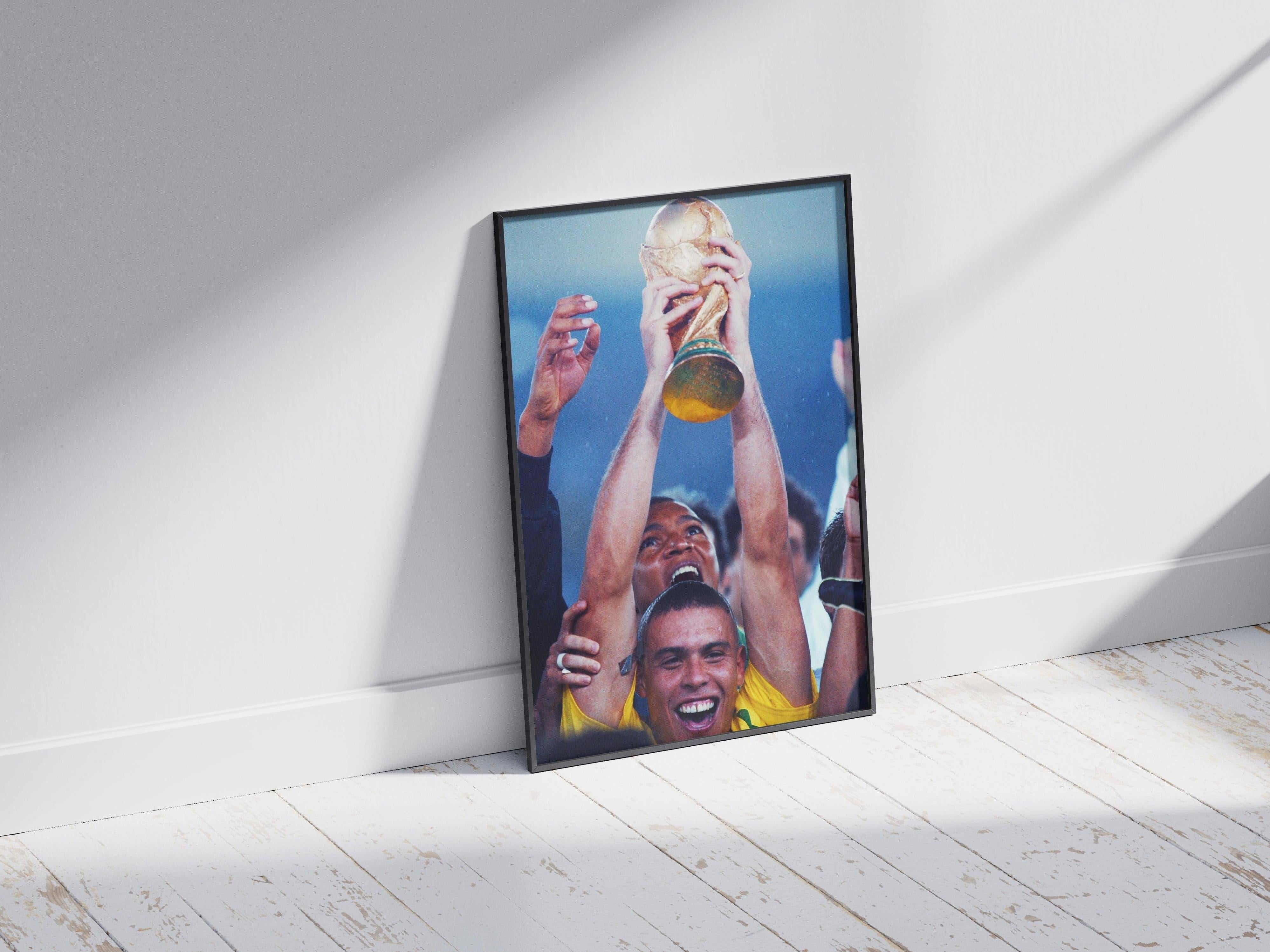The R9 x World Cup Poster from Retro1999 features a jubilant Brazil player in a yellow jersey holding a gold trophy, celebrated by teammates—a vibrant football photo print perfect for fans and sports decor.